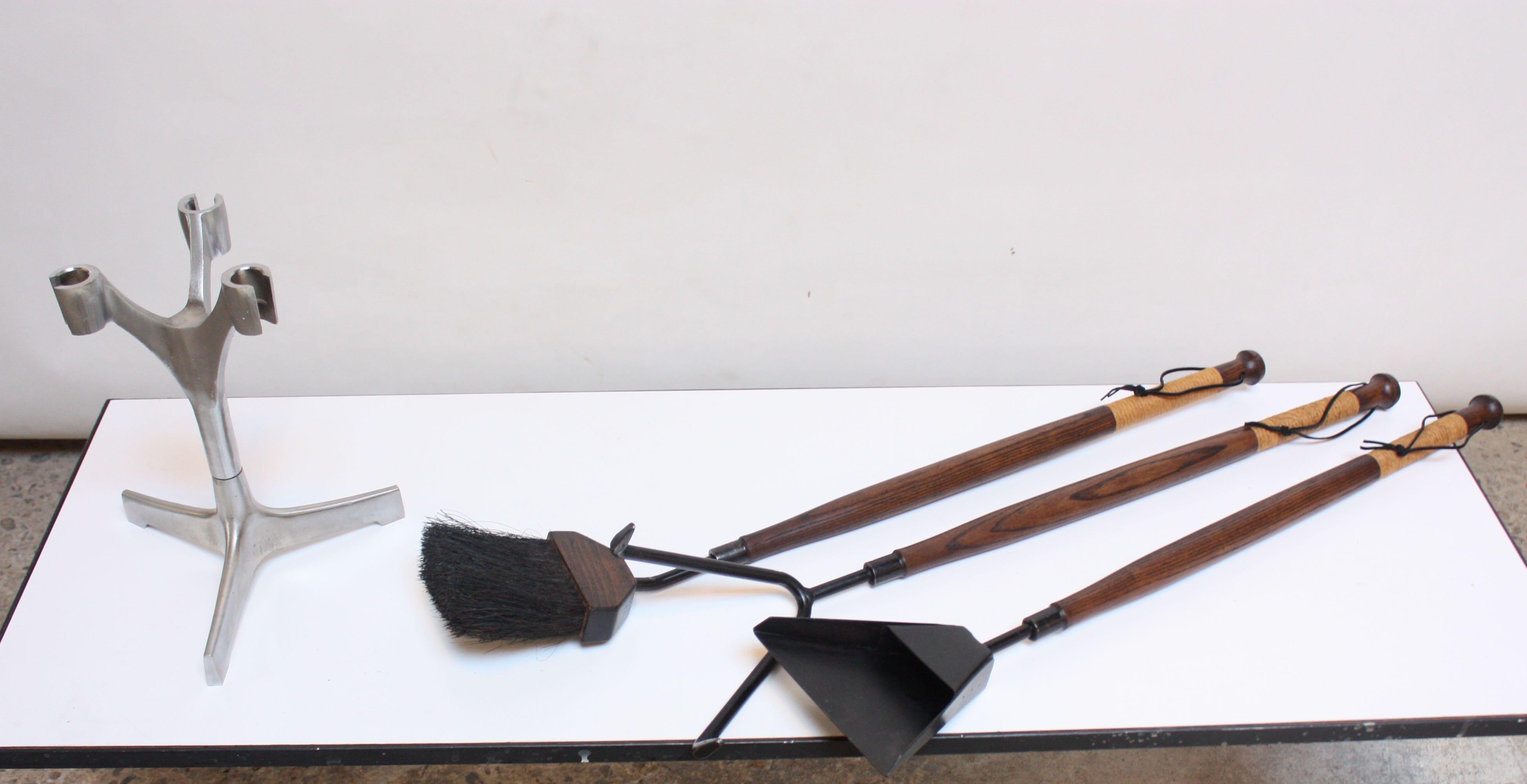 1950s American modern fire tool set composed of an iron broom, dustpan and poker, all with stained ash stems and original cane-wrapped handles with ebony leather loops. Includes original brushed-aluminum holder. Wood has been refinished and leather