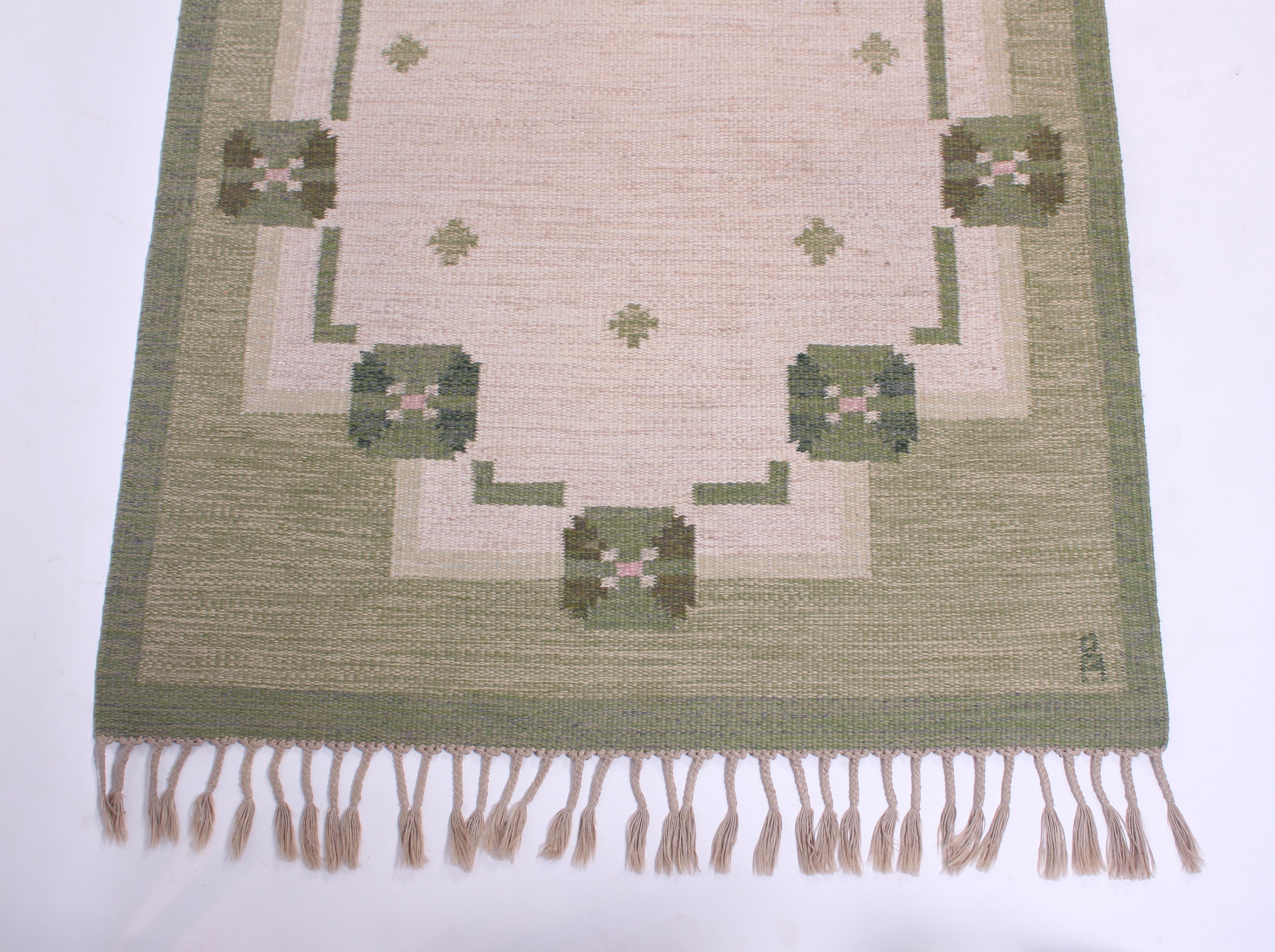 A midcentury flat-weave carpet designed by Swedish designer Anna-Johanna Ångström. The carpet green base and patterns of different green shades and an off-white/grey. Very good vintage condition with original lashes and minor signs of usage.