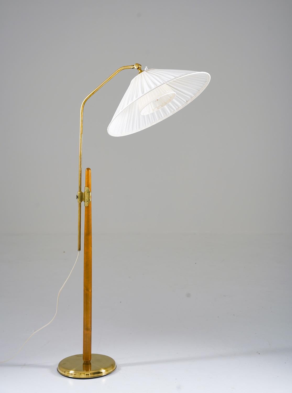Lovely floor lamp manufactured by Liberty, 1940s. 
The lamp consists of a wooden pole, supporting a brass rod that is adjustable in height. 

Maximum height is 160cm (55