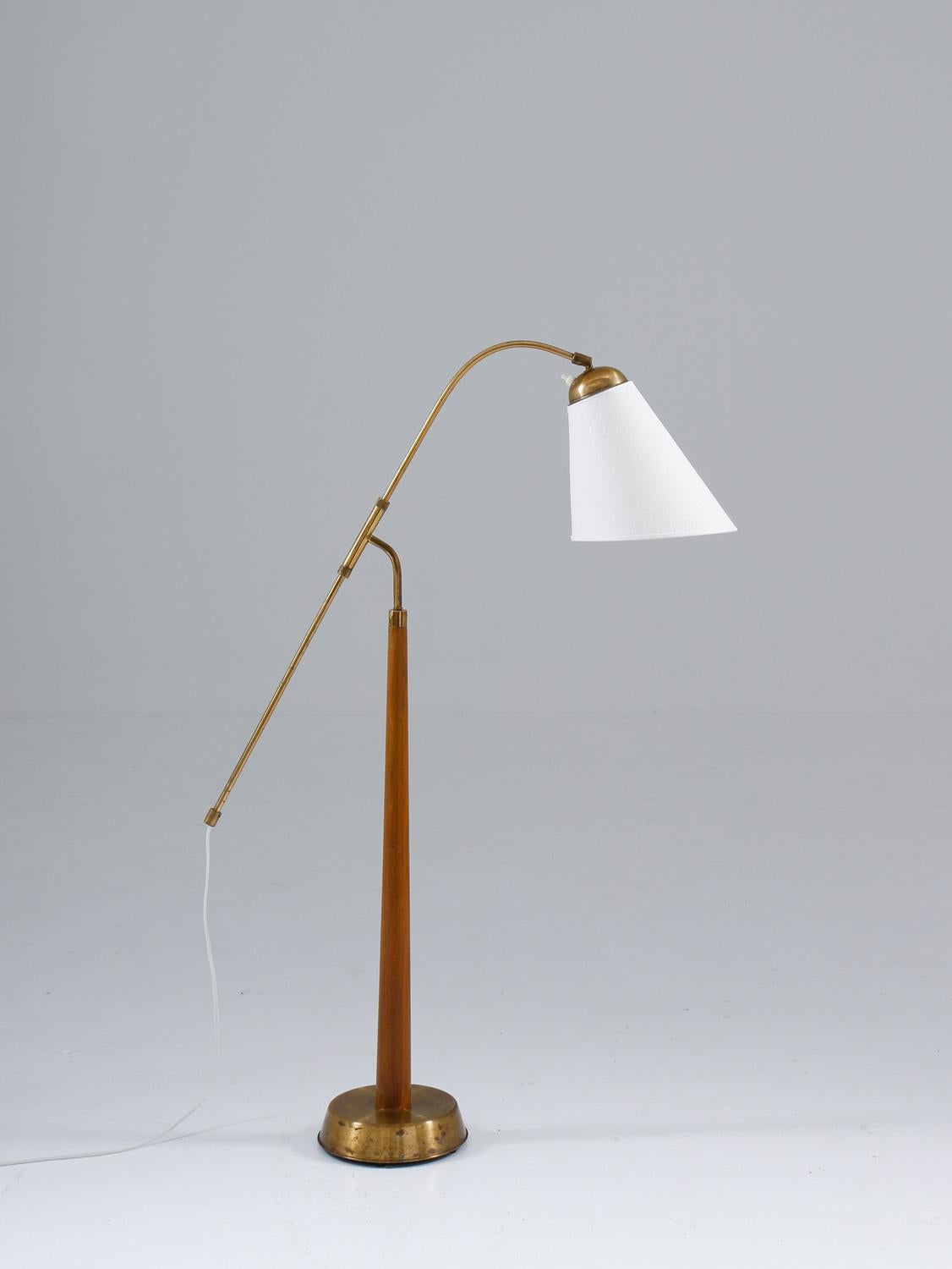 Very rare floor lamp model 512/1 in brass and wood by Ystad Metall, Sweden.
This is one of the few lamps produced by Ystad Metall. The lamp consists of a brass and wooden base, supporting a brass rod that is adjustable in height. 

Maximum height