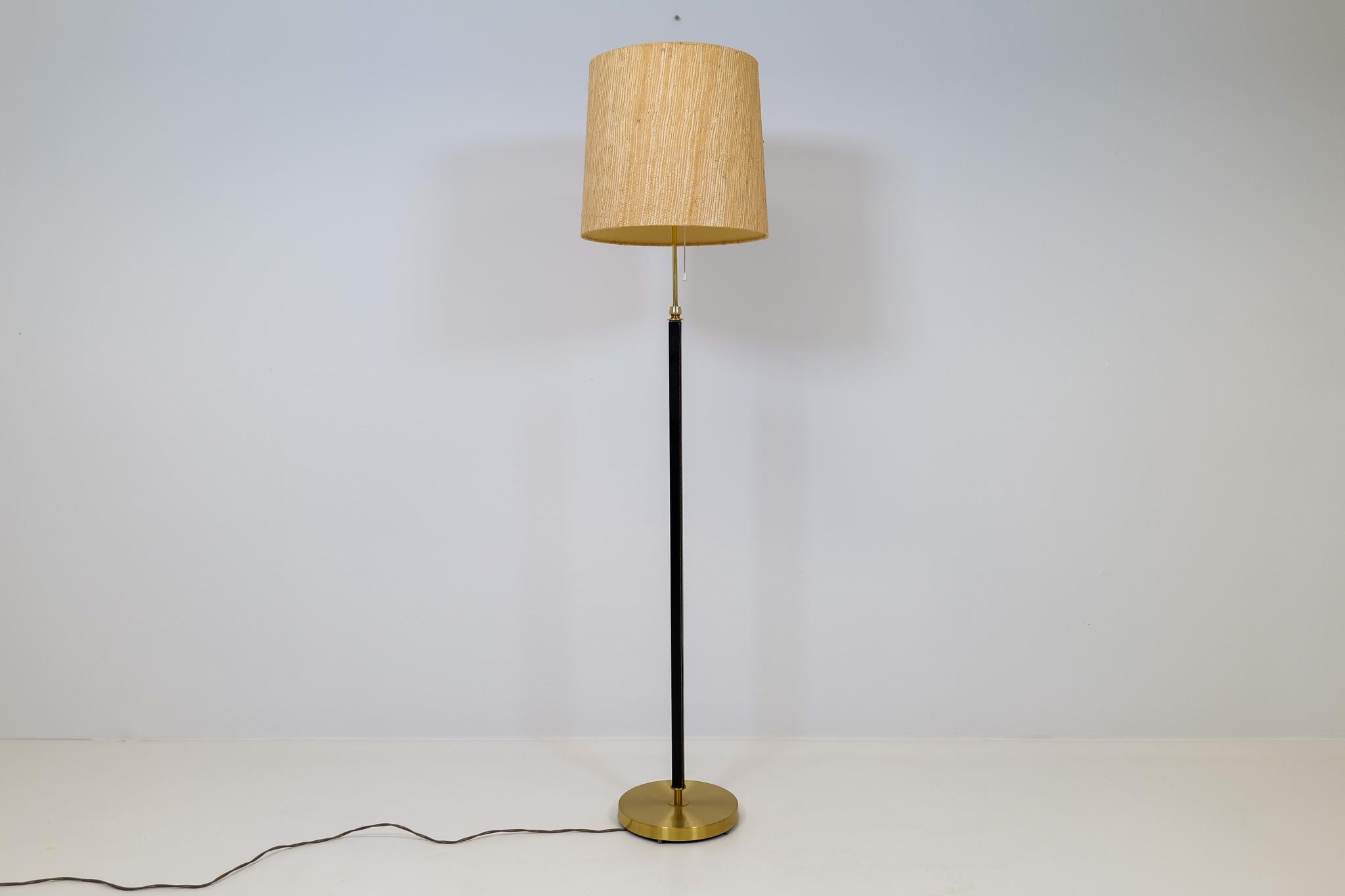 This lamp was made in Sweden at Falkenbergs Belysning. The combining of brass and black stained leather makes this lamp an icon. Original shade works good with the structure of the lamp.

Good working condition with some dents on the foot and