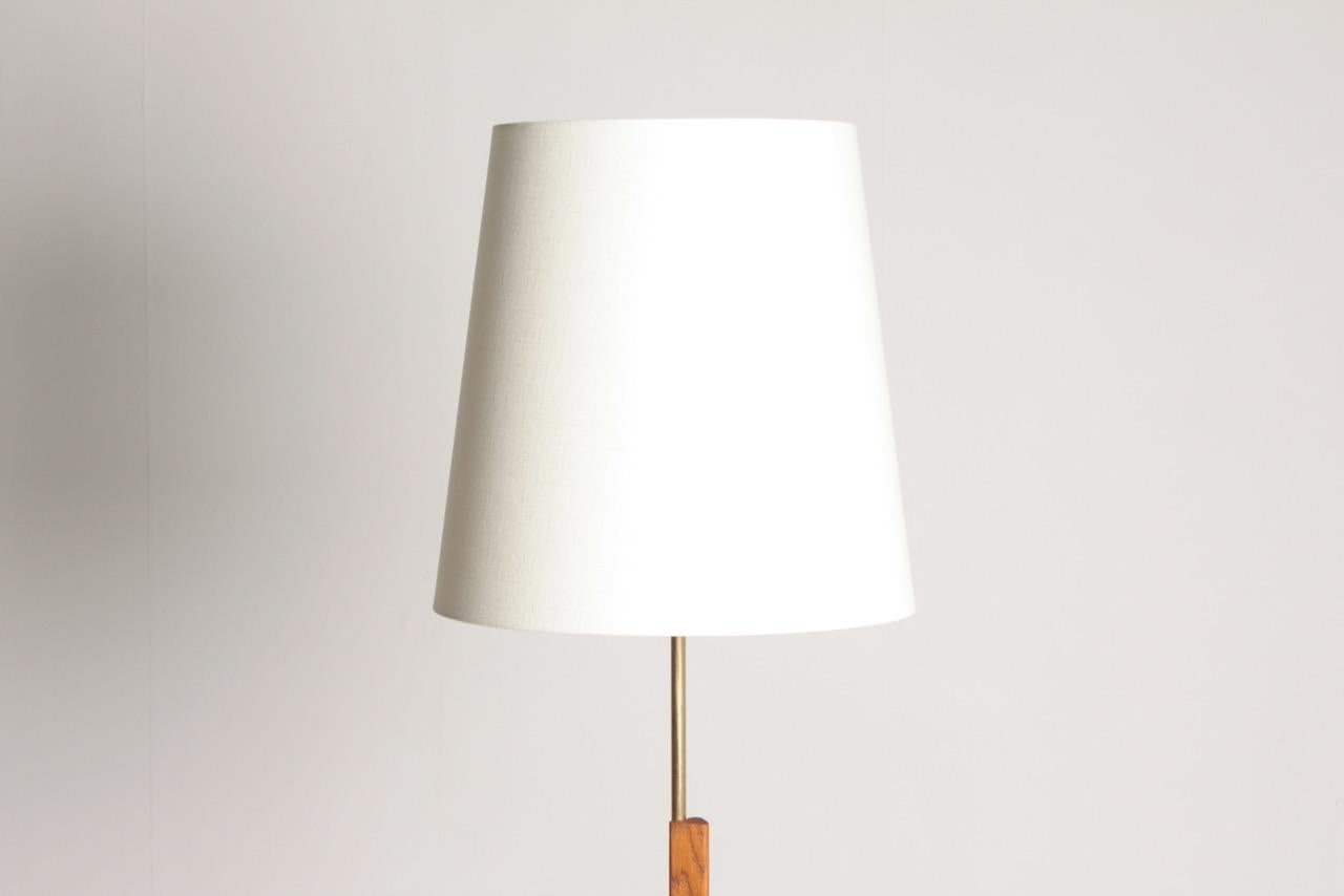 Height adjustable floor lamp in oak and brass on a black metal base, designed and made by Holm Sorensen, Denmark in the 1950s. Great original condition.