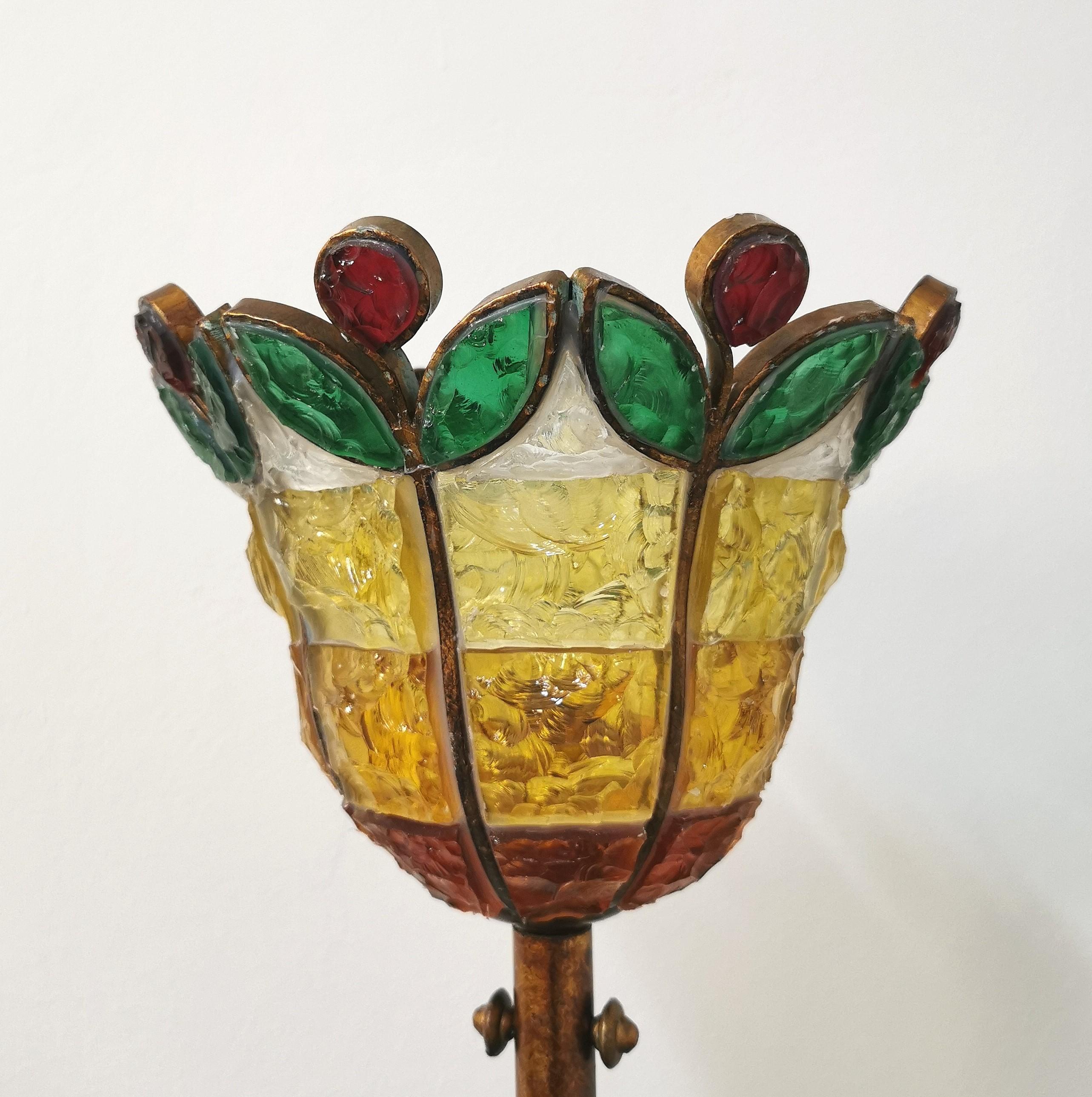 Floor lamp produced in Italy in the 70s by the Italian company Poliarte. The lamp has a circular base and a long stem in bronzed metal with a hammered glass diffuser in shades of yellow, green, red and transparent.