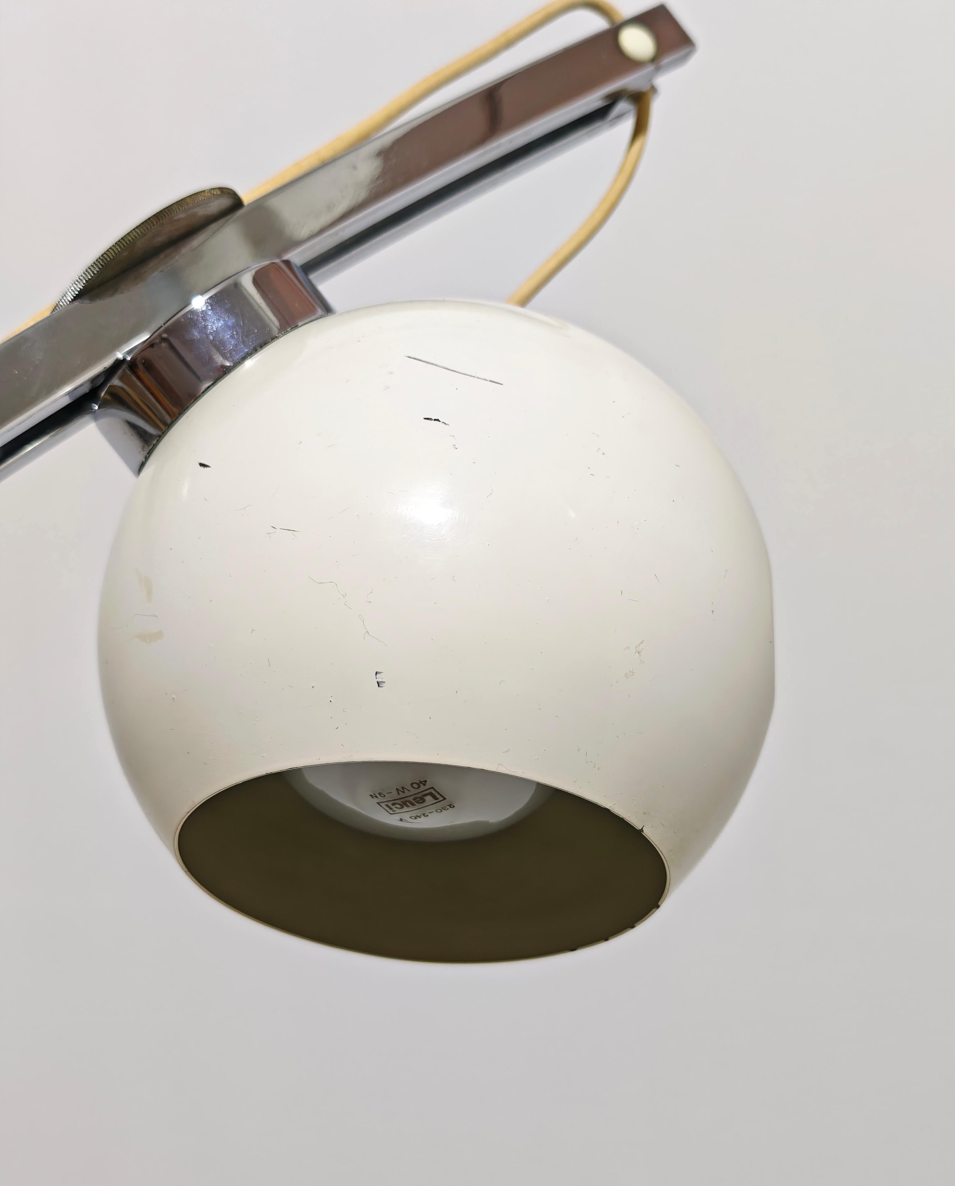 Lámpara de pie de diseño al estilo de Goffredo Reggiani, fabricada en Italia en los años 70. La lámpara tiene una base circular de metal esmaltado blanco, donde se apoya un tallo curvado de metal cromado, que gracias a su alambre y su imán sostiene