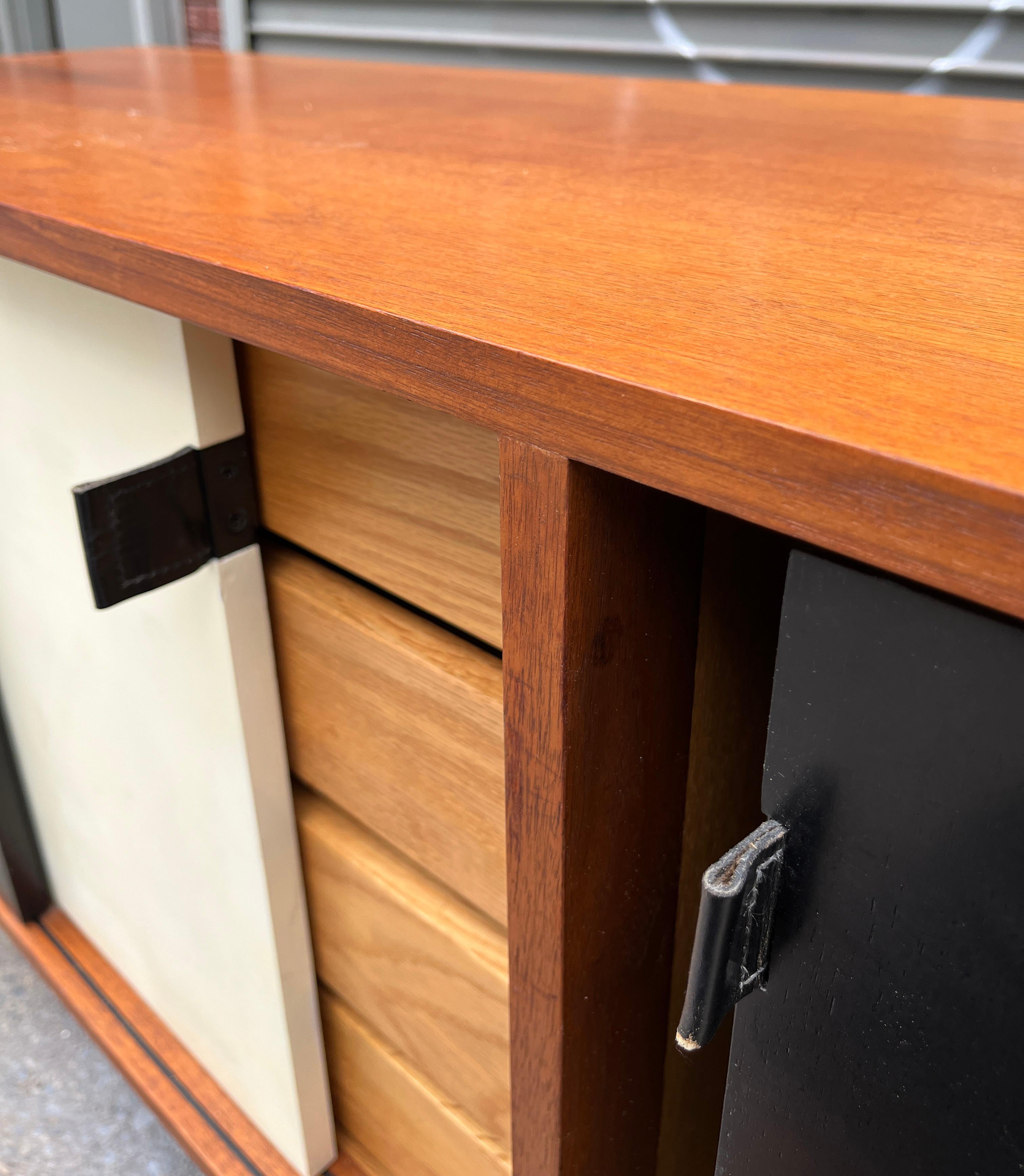 Bonito y práctico aparador para el salón o el despacho. Las puertas correderas en damero con tiradores de piel revelan una posición de 4 cajones y 3 secciones de estantes ajustables. Perfecto para tus necesidades de almacenamiento. El armario es de