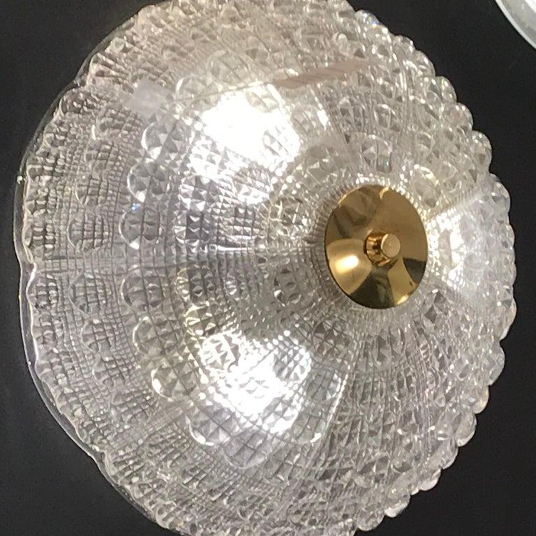This elegant midcentury flushmount chandelier was designed by the legendary Carl Fagerlund for Orrefors in Sweden, circa 1960. It features a stunning pressed glass dome with a subtly scalloped top and a wealth of organic texture through with a