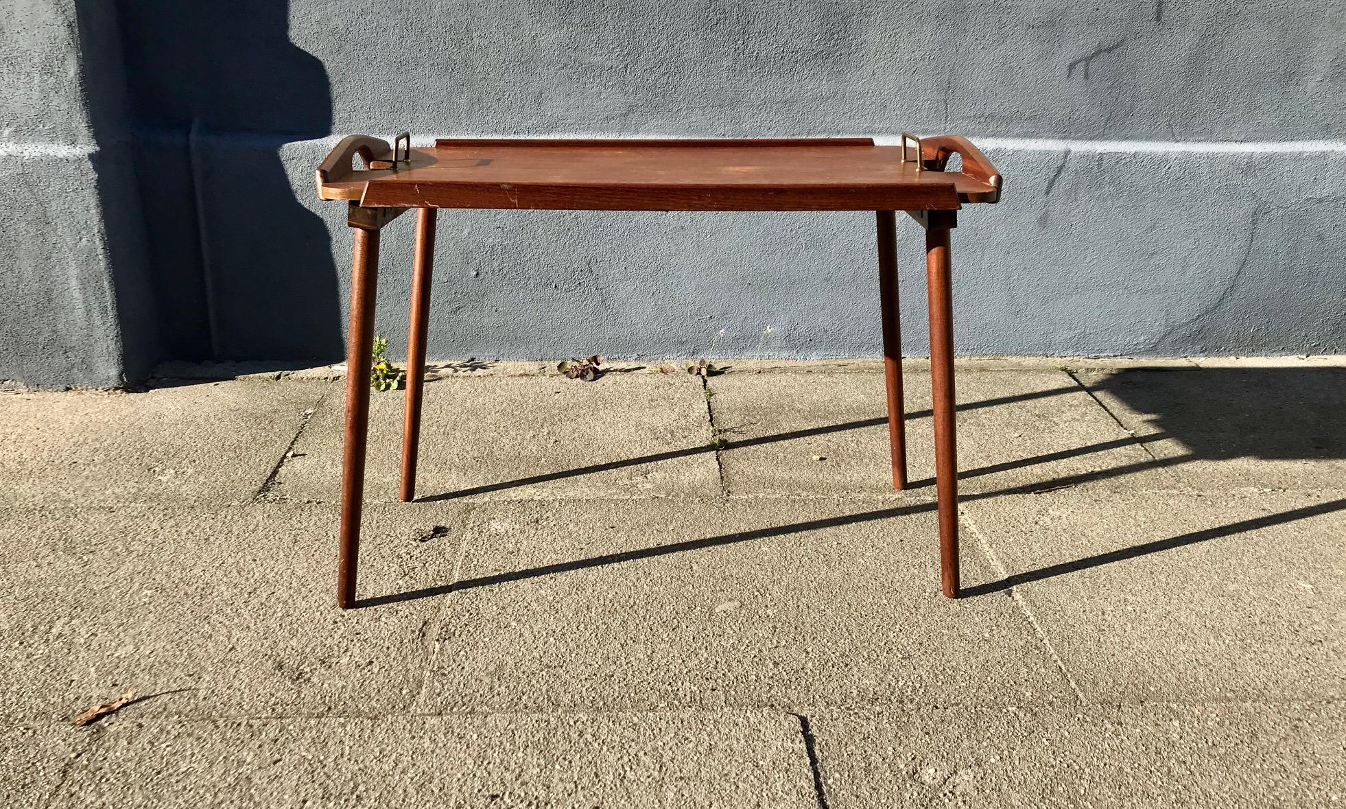 'Tixi' - rare foldable teak, oak and brass tray designed by Bendt Winge in the 1950s and manufactured from circa 1960 by Aase Dreieri in Norway. The features foldable legs that via a mechanism to the back 'sucks' the legs in to a flat position. It’s