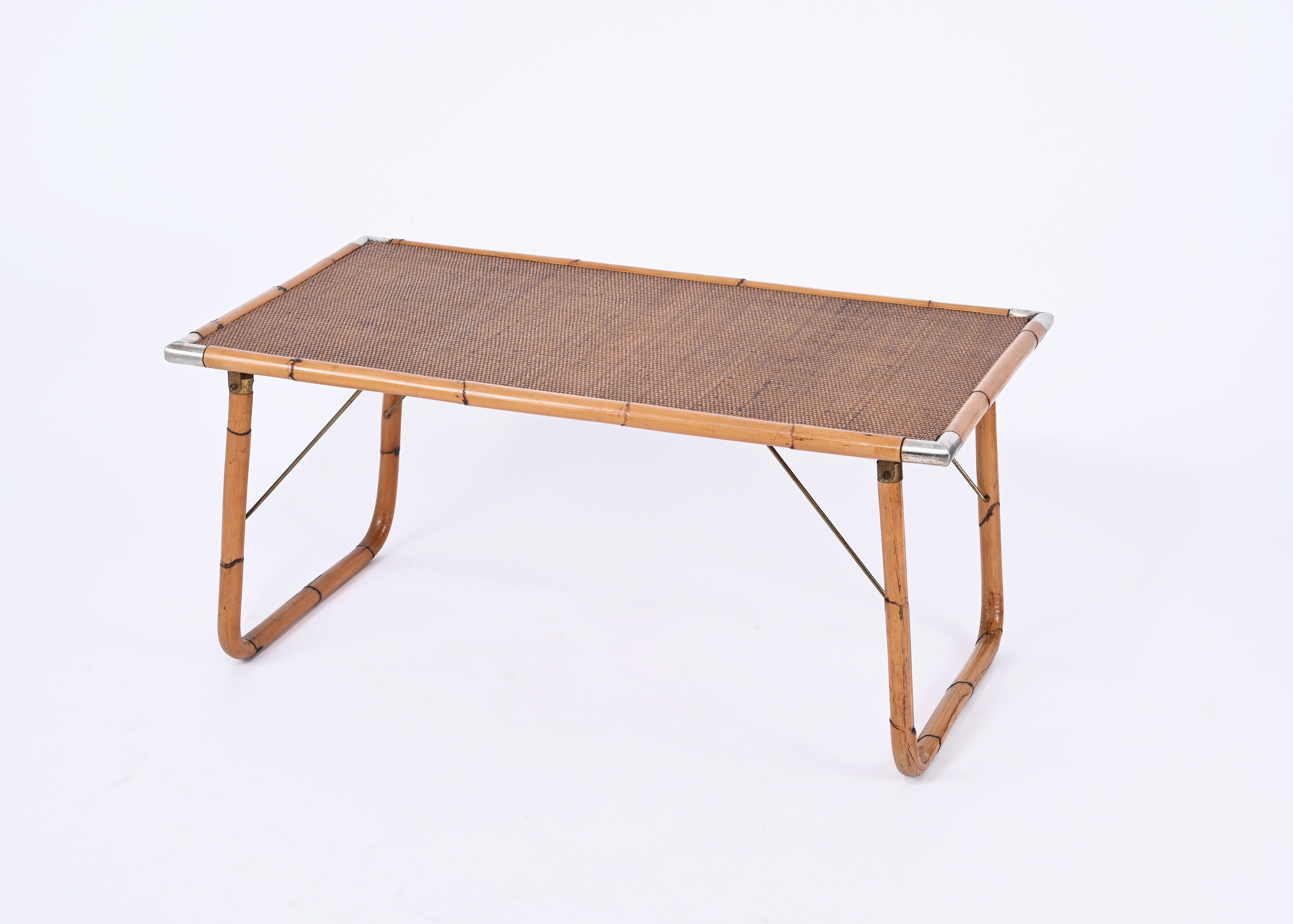 Stunning midcentury foldable coffee table in bamboo cane and wicker with polished metal corners.  This coffee table was designed in Italy in the 1960s.

This lovely piece is fantastic as it is very solid and eclectic, it can be easily folded and