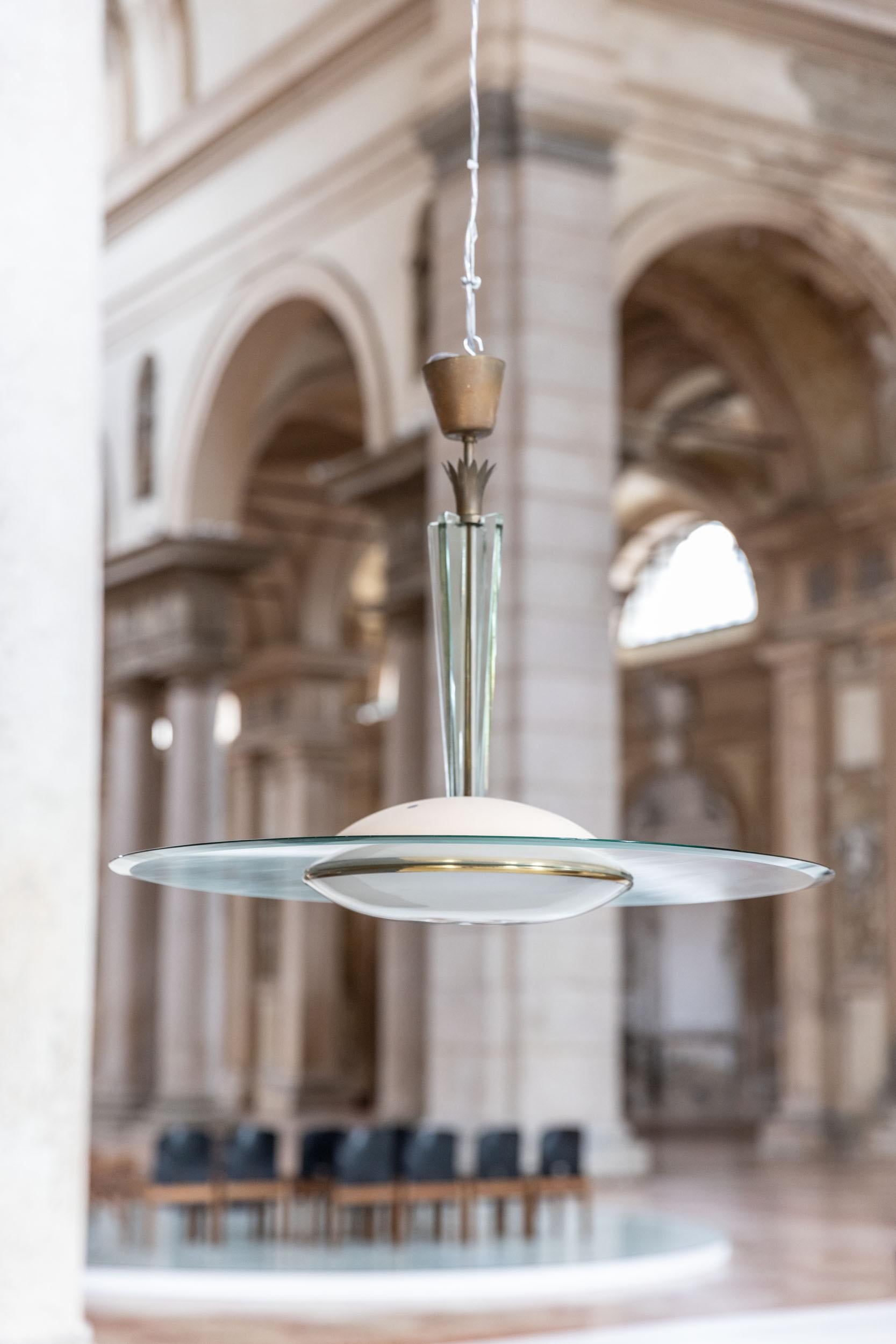 Stunning chandelier designed by Gio Ponti for Fontana Arte 
This suspension lamp, manufactured by Fontana Arte, features a transparent glass disc with metal and brass details 
Original opaline glass and structure
Italy 1940