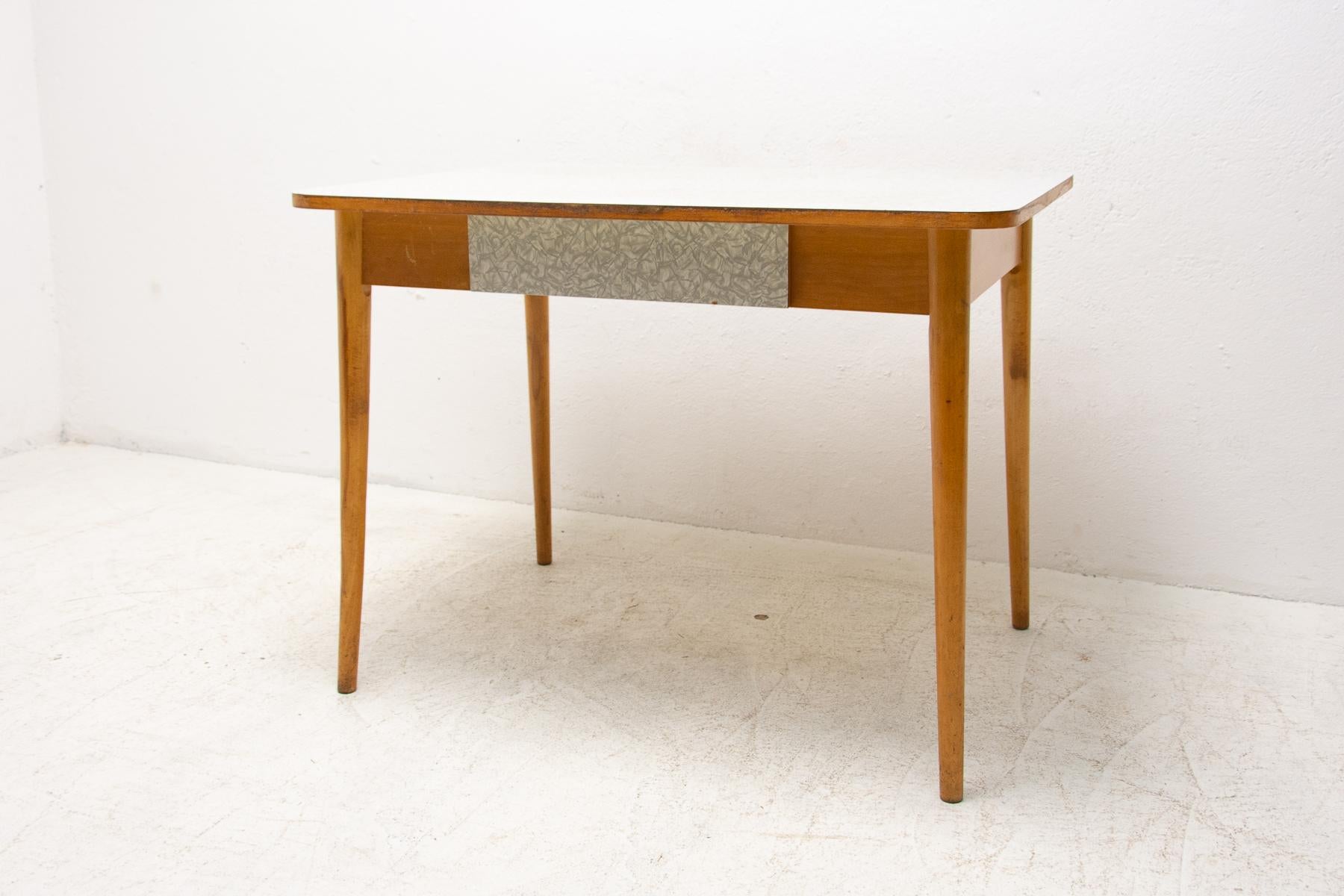 Mid-century central table with a formica plate, beech legs and one drawer. It can be used as a writing desk as well. It was made in the former Czechoslovakia in the 1960´s. In well preserved Vintage condition, shows signs of age and