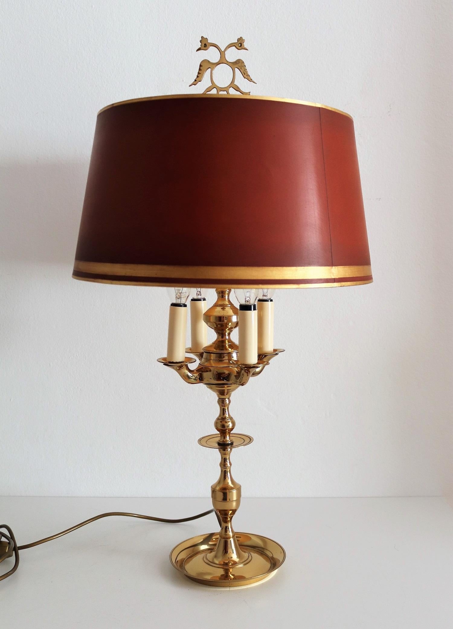 Gorgeous Bouillotte table lamp made of full brass during the midcentury, but in the style of Louis XVI.
The lamp has four arms for small candelabra light bulbs.
The top ends up with an eagle shaped detail, also of full brass.
The lamp shade in