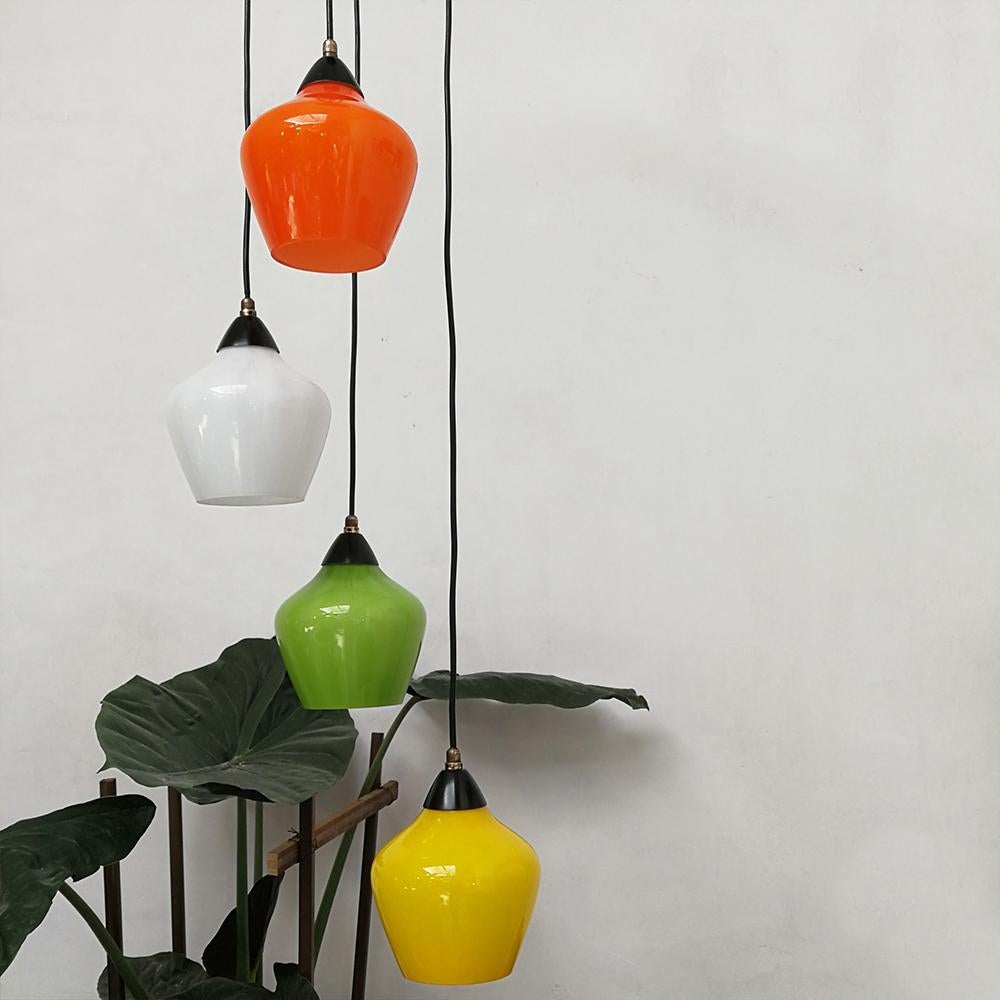 Midcentury four-lights colored glass ceiling lamp, 1950s
Amazing italian multilights chandelier dating to the 1950s. Four glass lampshades in different colours are suspended at different heights starting from the same black metal holder, with brass