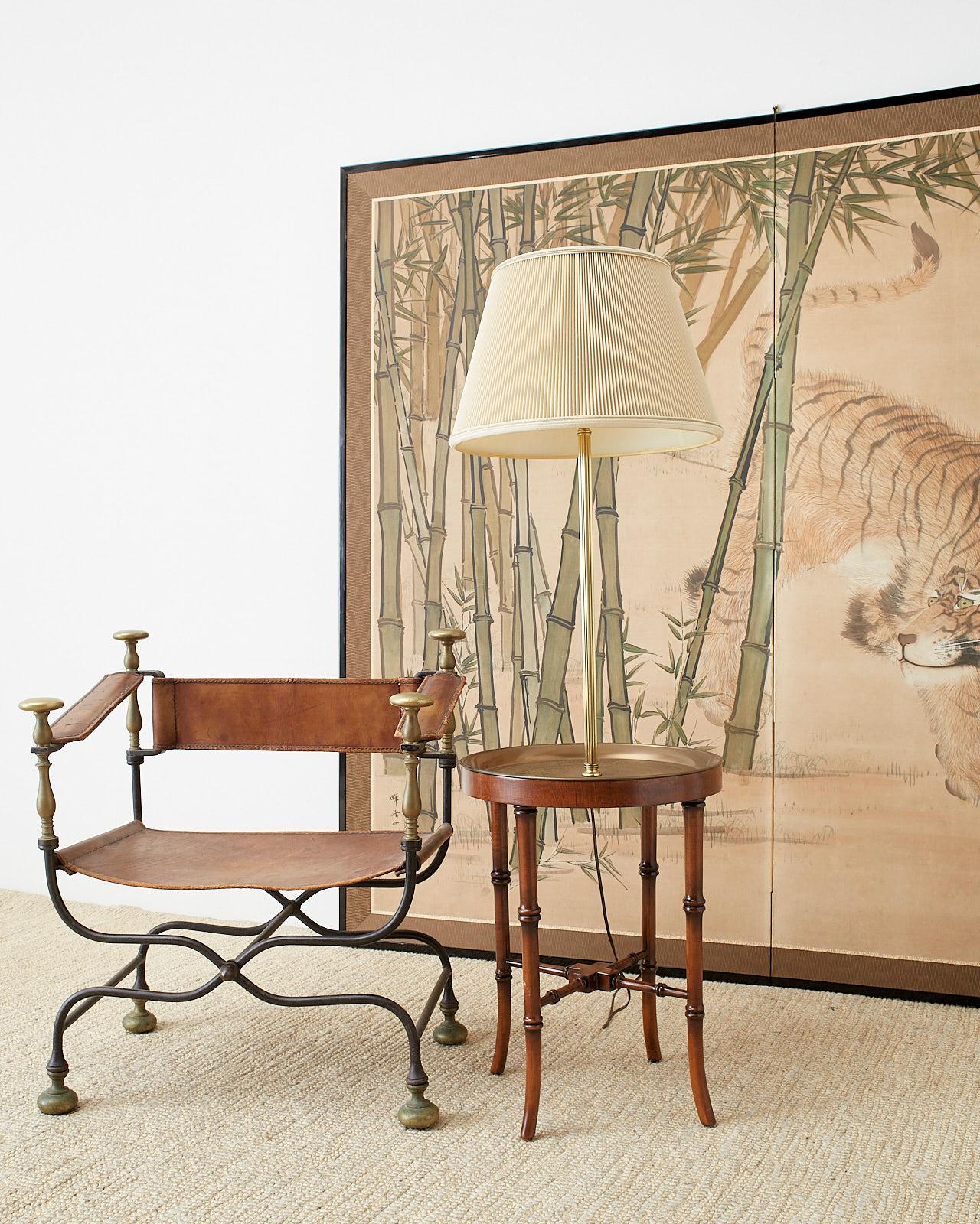 Asian inspired faux bamboo floor lamp by Frederick Cooper features etched brass tray table with a Chinese scene surmounted by a tall brass fluted column with a shade. Supported by a carved wood faux bamboo base having four legs conjoined with a