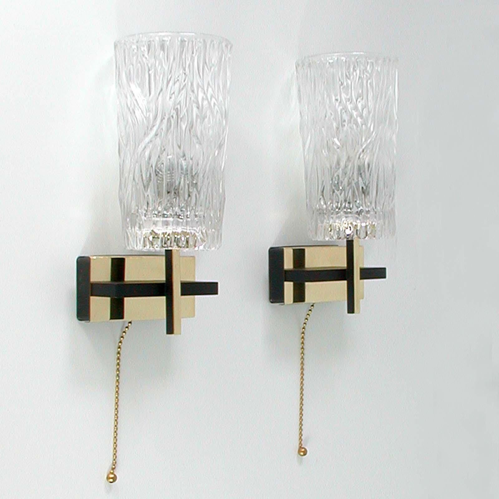 This awesome pair of French sconces was produced by Maison Arlus in the 1950s. The lights are made of brass, black lacquered metal and have got thick textured glass lamp shades. 

The lights require a E14 bulb each. They have been polished and are