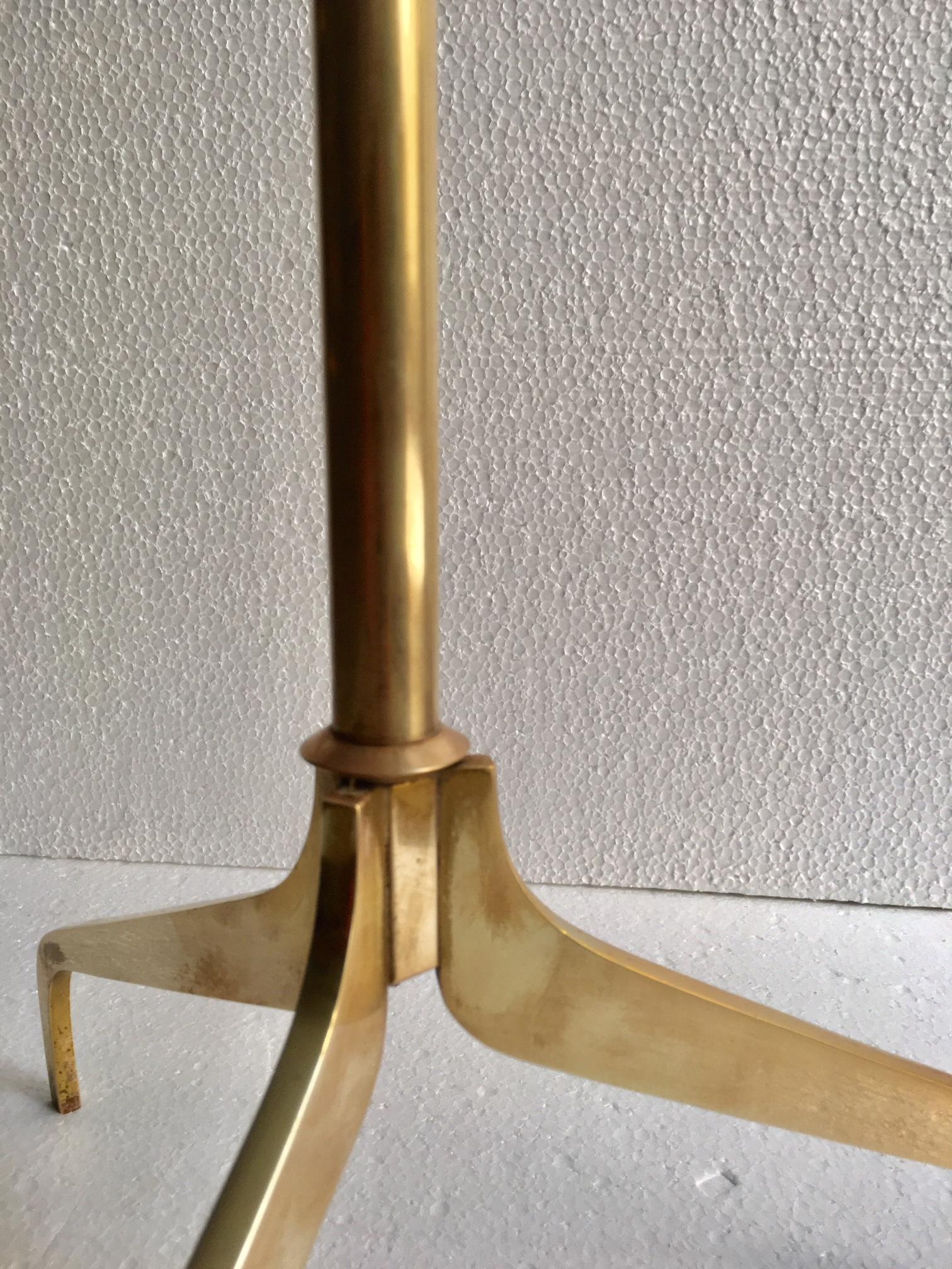 Very elegant floor lamp from 1950, brass supported on a brass tripod base, the lamps is adjustable and extended, the shade in black and gold interior.