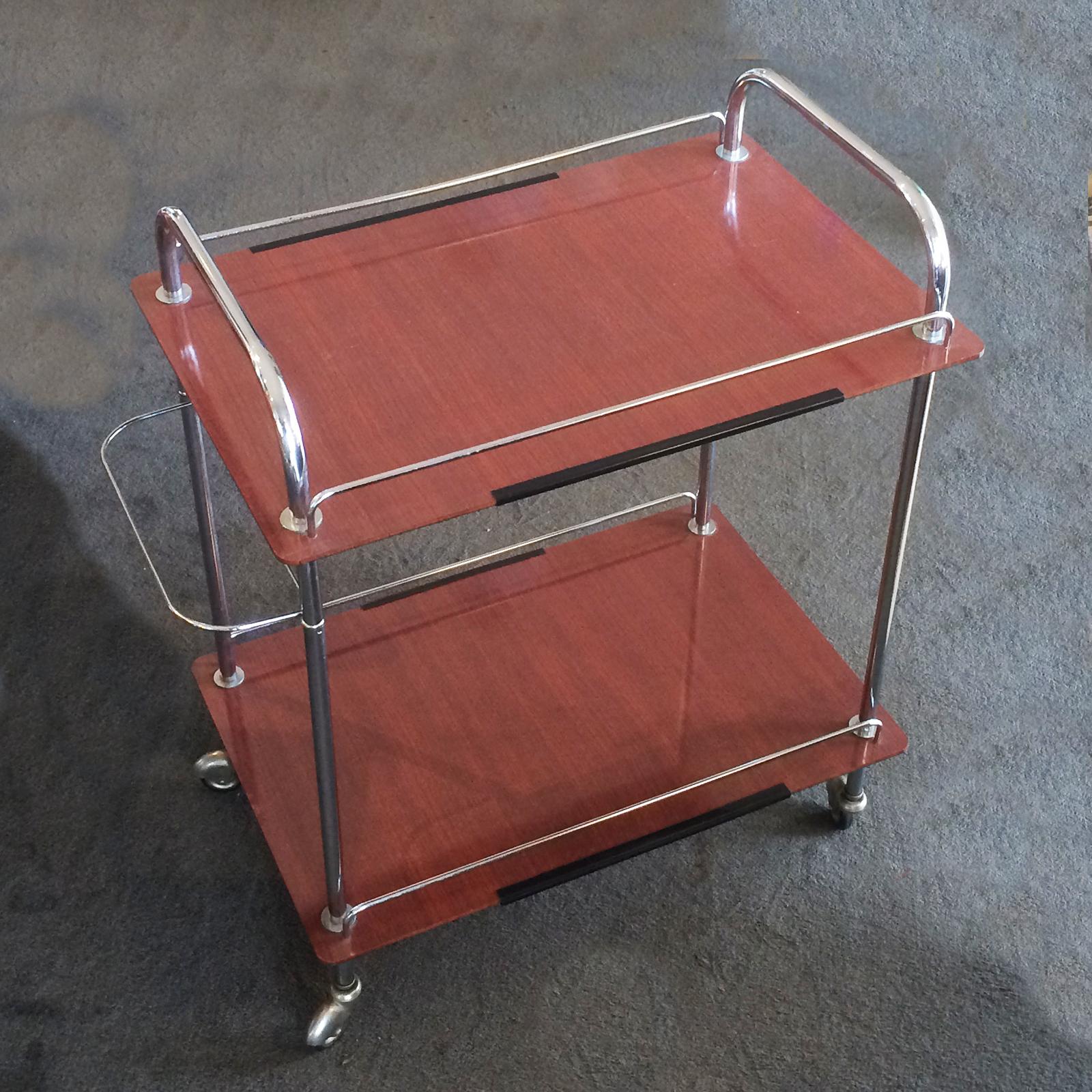 Midcentury French rolling bar cart, in chrome with nickel hubcaps and two shelf levels of display in brown woodgrain finish. It has a lower Towel rail at rear which is a useful addition, which is not on all other trolleys. The wheels run easily, are