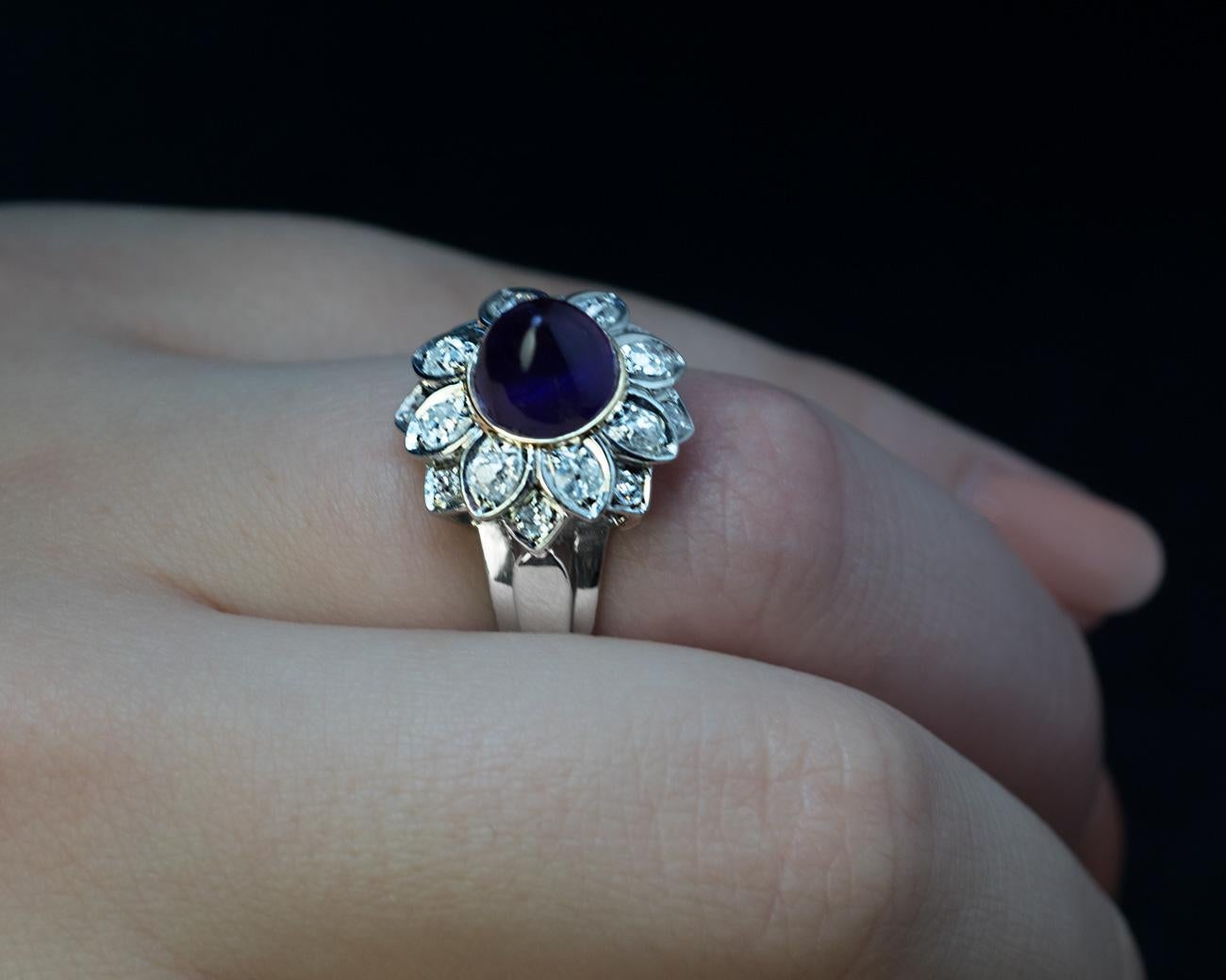 France, 1950s

A vintage platinum and gold ring is designed as a flower head with a cabochon amethyst center and diamond set petals. The cabochon cut amethyst of a dark purple color is set in a yellow gold bezel.

The amethyst measures 8 x 8 x 7.3