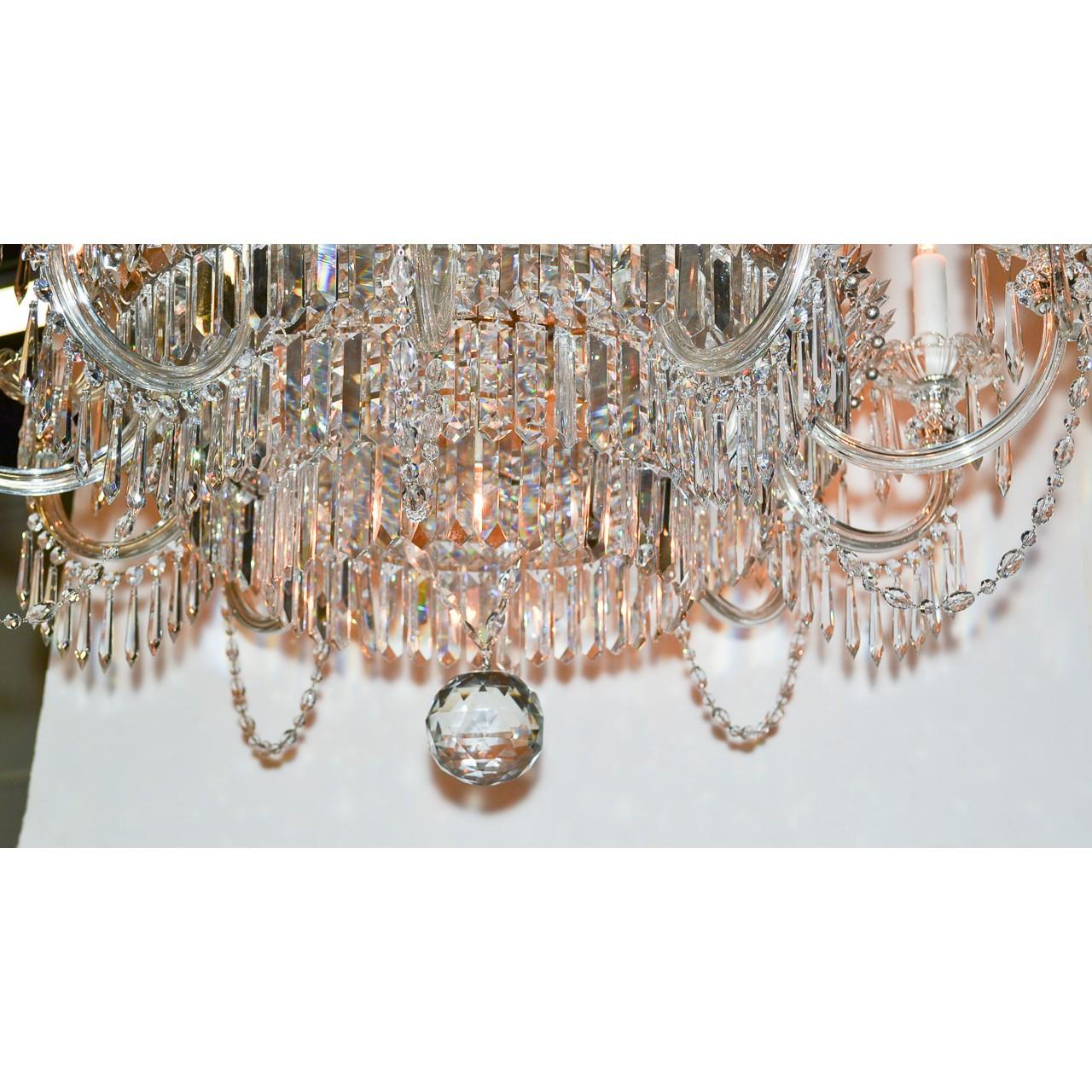 Remarkable continental crystal fifteen-light chandelier with a beautifully draped crown featuring clusters of icicle prisms and starburst crystal accents. The shaped cut crystal stem having an upper tier with candle drop lighting and starburst