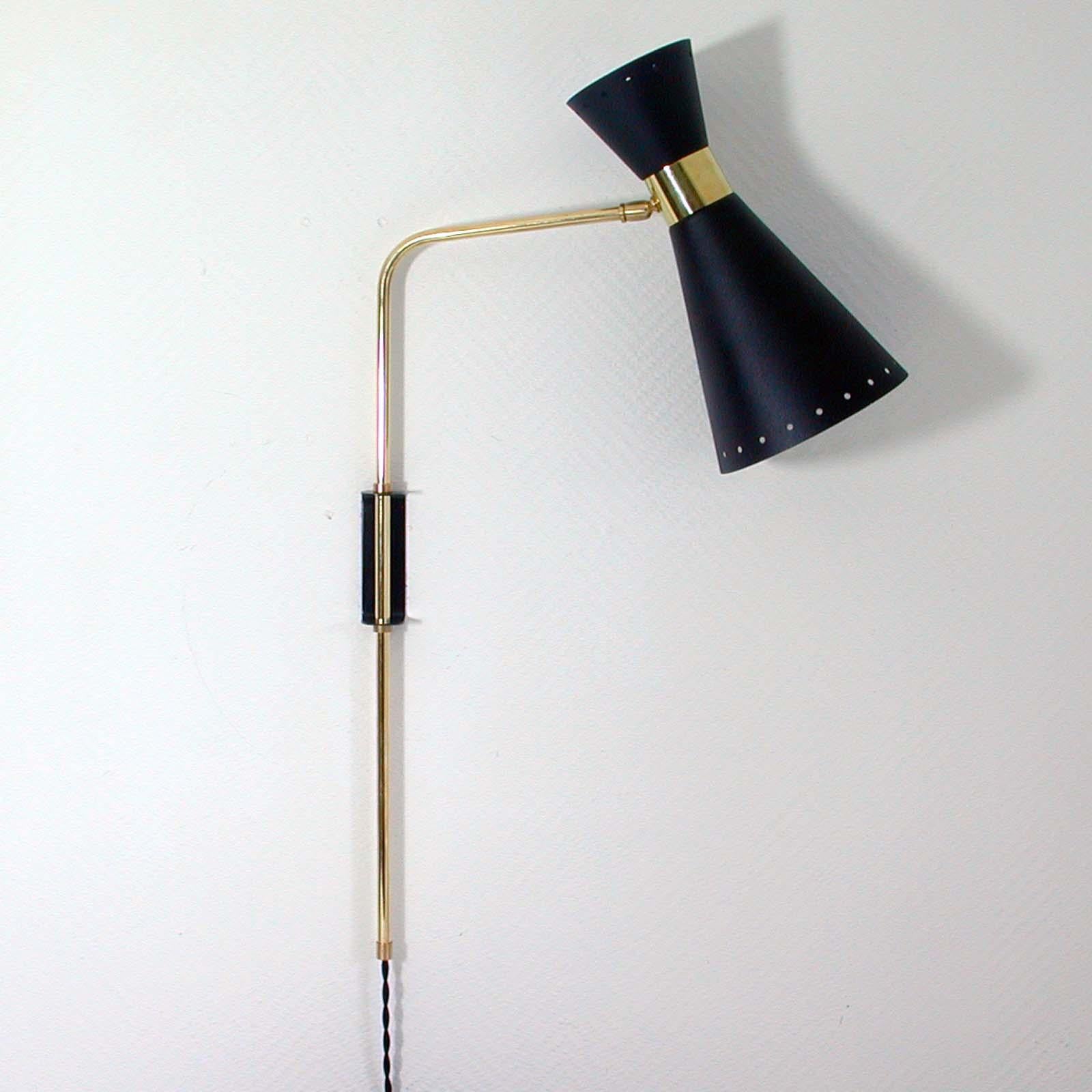 This awesome Pierre Guariche style articulating wall lamp with adjustable shade and height adjustable lamp arm was made in France in the 1950s. The light features a lampshade made of black lacquered metal with brass details. The swiveling and