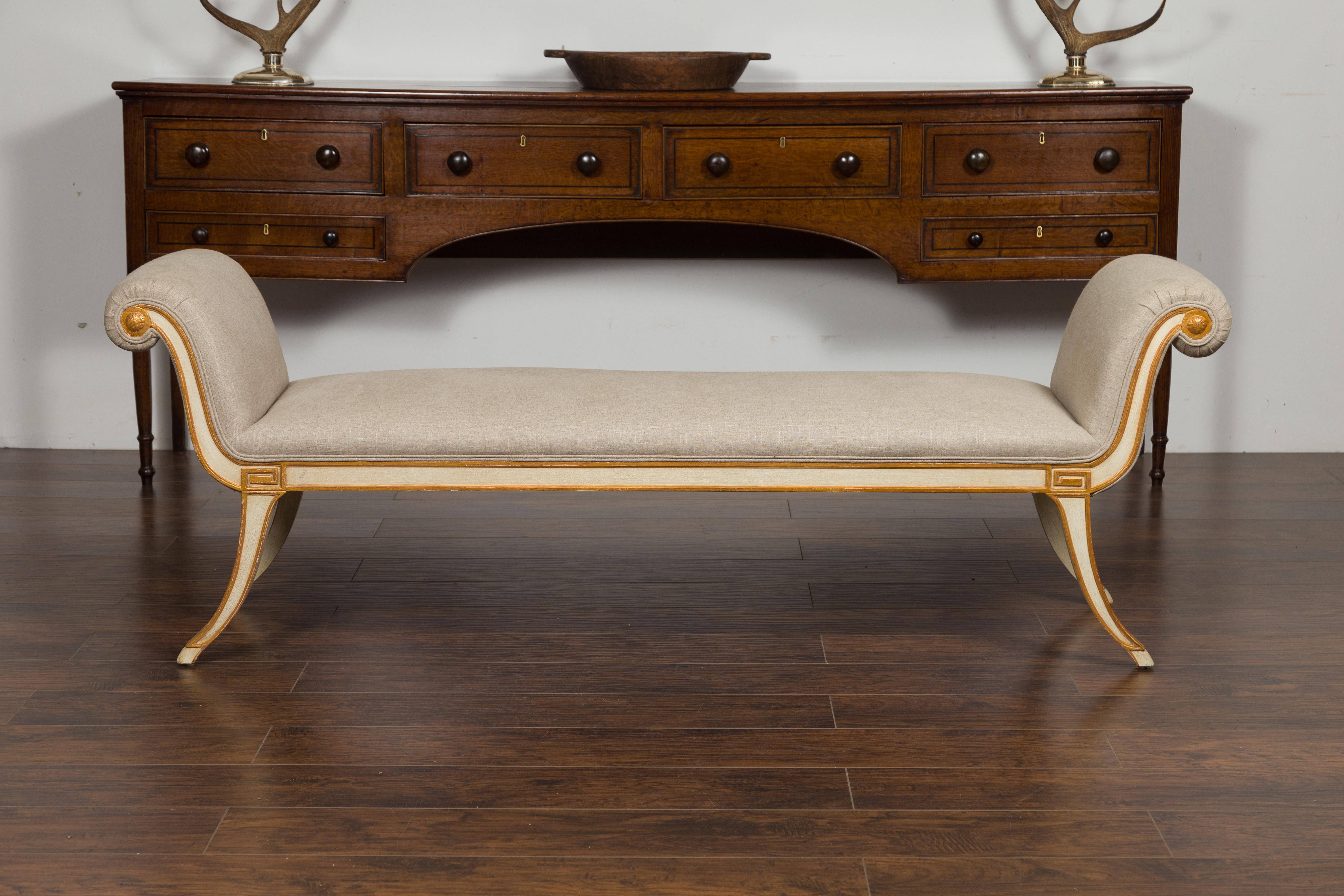 A vintage French Empire style painted and gilded bench from the mid-20th century, with out-scrolling arms, saber legs and new upholstery. Created in France during the midcentury period, this Empire style bench features two out-scrolling arms