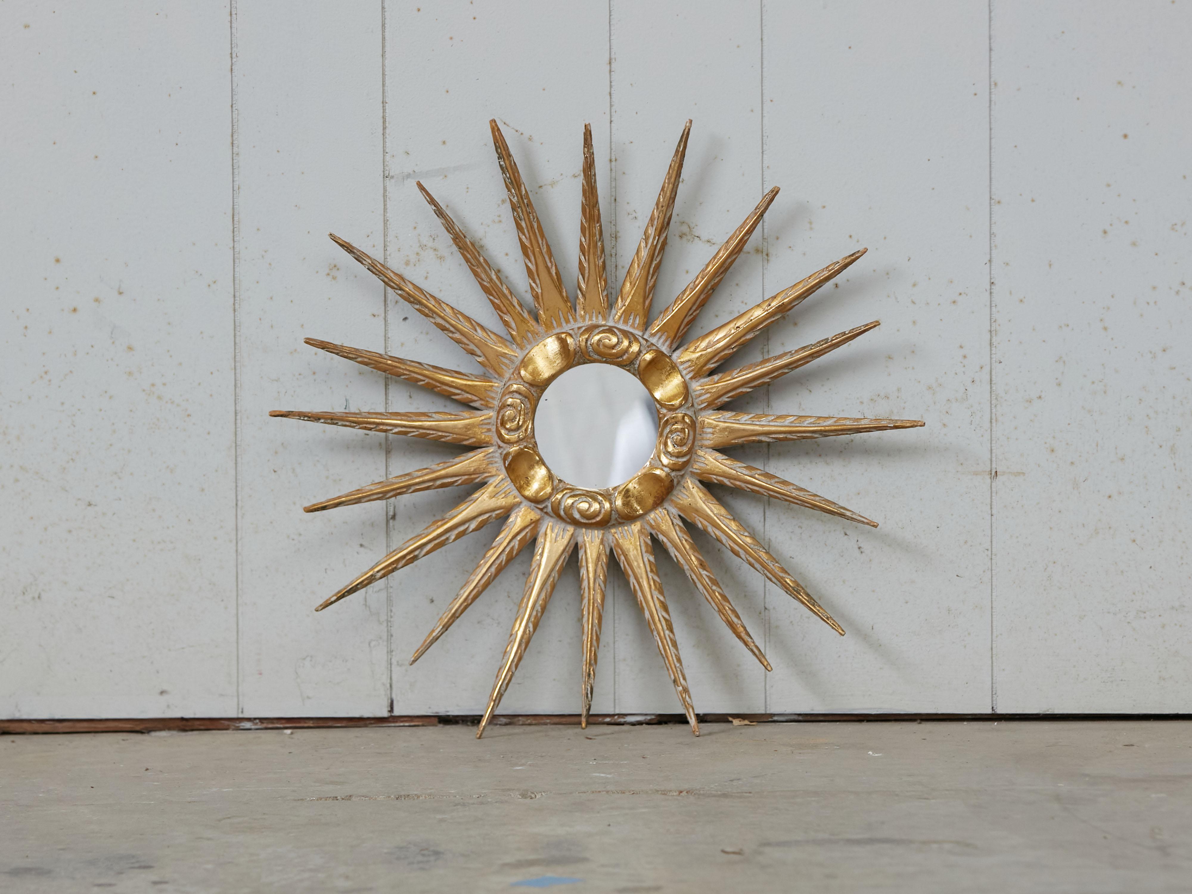 A French giltwood sunburst mirror from the Midcentury period, with cloudy frame and carved rays. Bask in the radiant beauty of this French giltwood sunburst mirror from the Midcentury period, a piece that artfully combines the brilliance of the sun