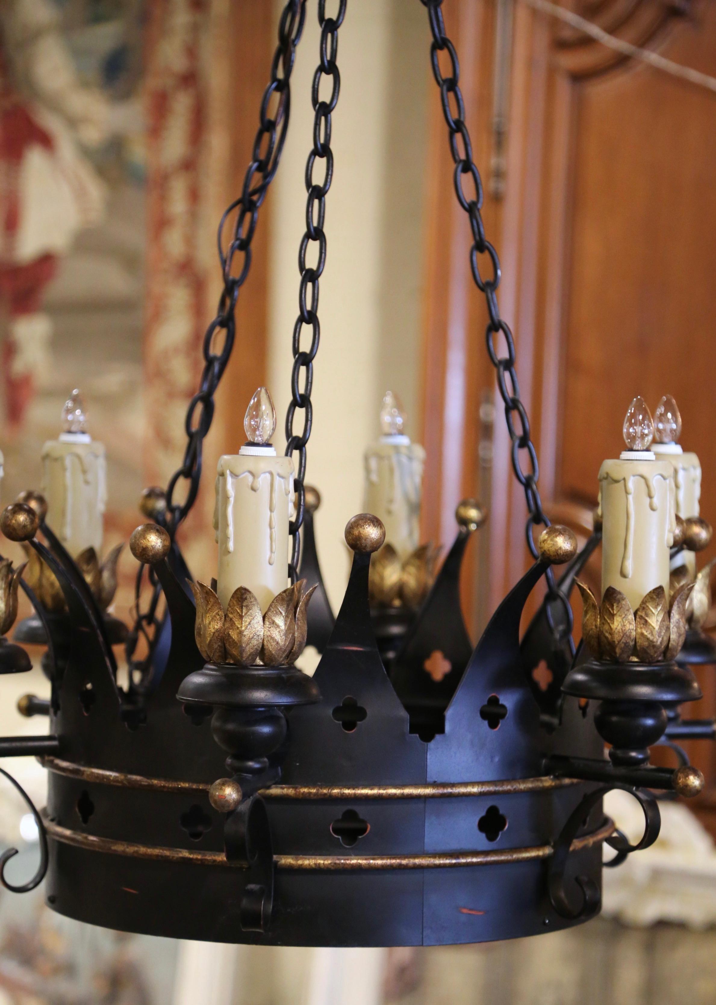 Diese komplizierte antike Eisenleuchte wurde um 1970 in Frankreich geschmiedet. Der runde gotische Kronleuchter hat eine kreisförmige, gehämmerte Krone, die rundherum mit Riegeln verziert ist und auf dem Coronet mit zahlreichen Zacken verziert ist.