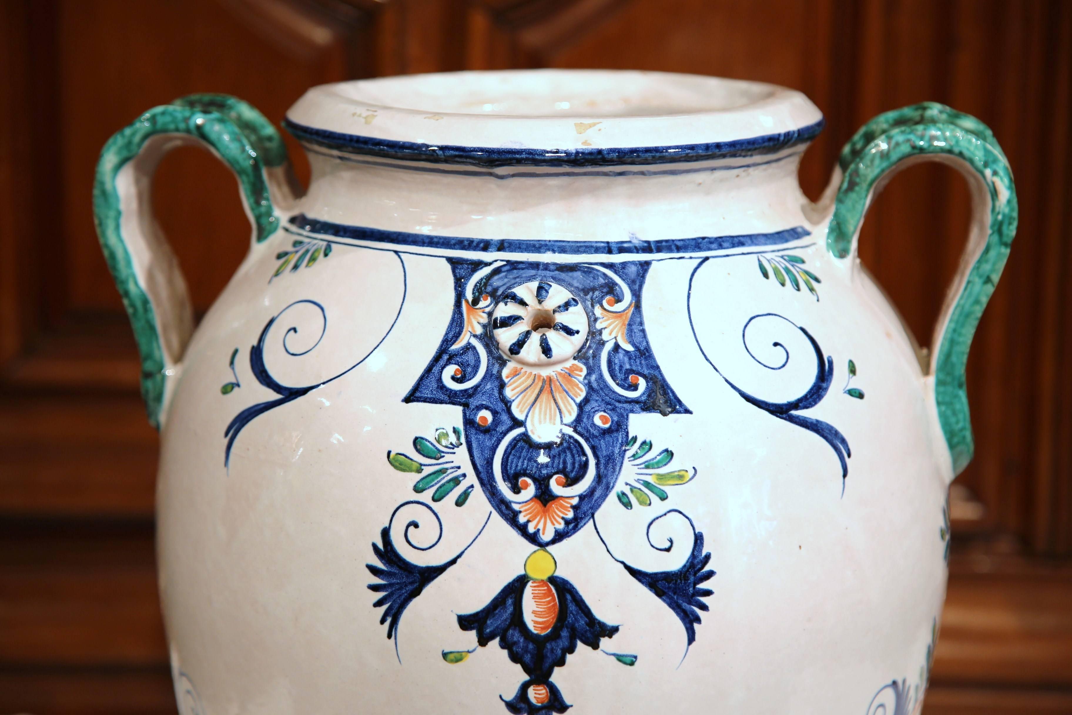 Verwenden Sie diese elegante antike Vase als dekorativen Schirmständer. Die hohe, tiefe Vase mit grünen Henkeln wurde um 1960 in der Normandie, Frankreich, hergestellt. Sie ist mit wunderschönen blauen, roten und weißen Dekoren im klassischen