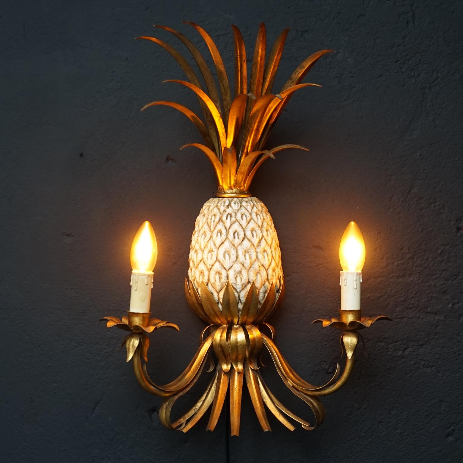 Very unique vintage Hollywood Regency style Pineapple wall light.
The pineapple part is made of withe ceramic, furthermore the lamp has gold colored metal leaves and light fixtures.

The Hollywood Regency style is famous for its material