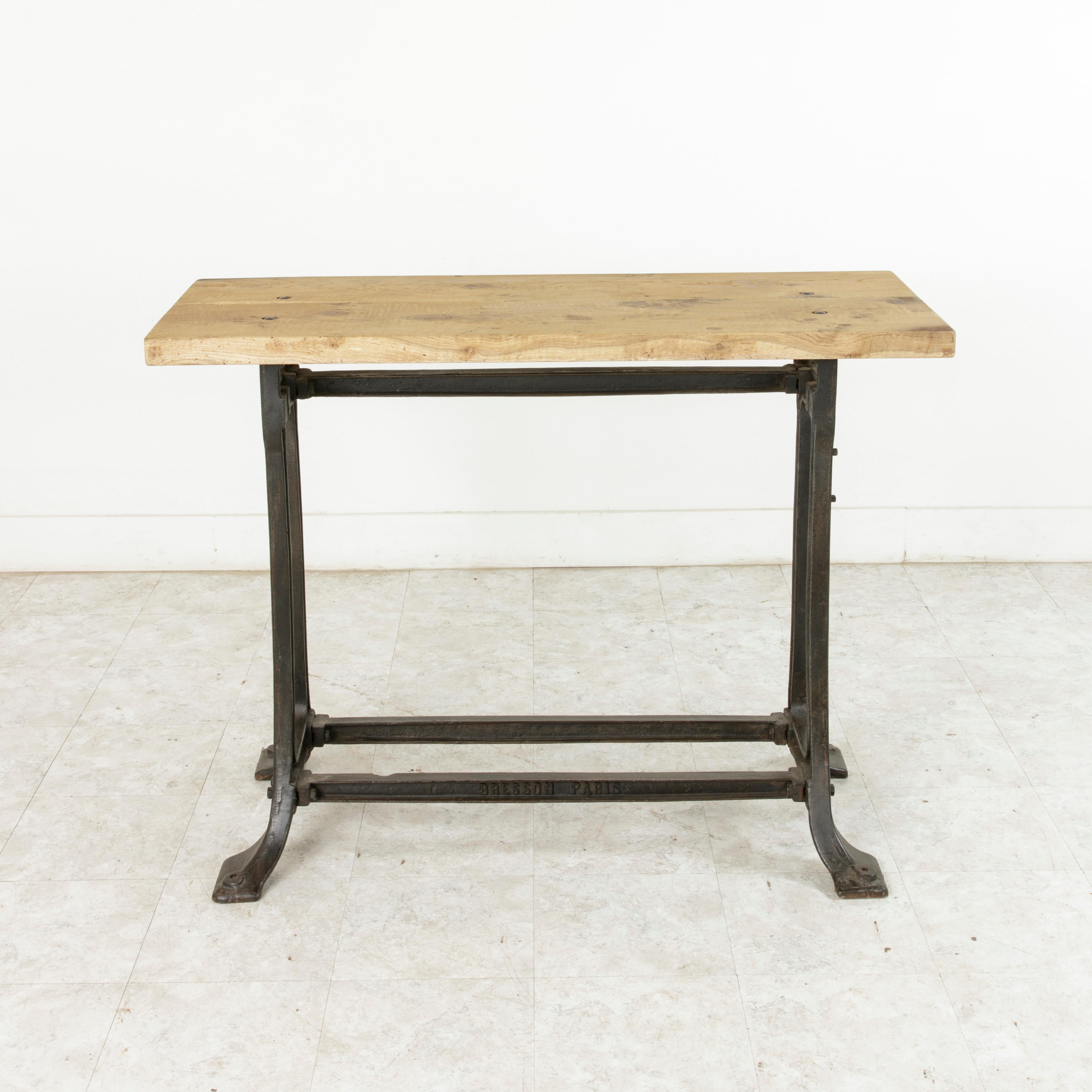 This early 20th century French Industrial console table or work table stands at 36.5 inches in height and features a two inch thick oak top constructed of two planks of wood joined by a spline that runs the length of the tabletop. The top rests on a