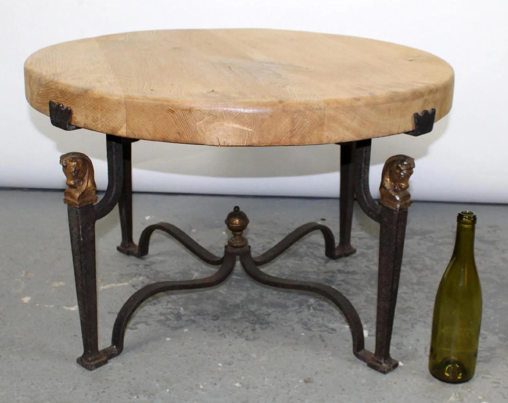 Midcentury French cocktail/coffee table with wrought iron base and natural finish oak top, in the style of Jean-Charles Moreux. The wrought iron base features gilt horse head capitals resembling chess knight pieces.