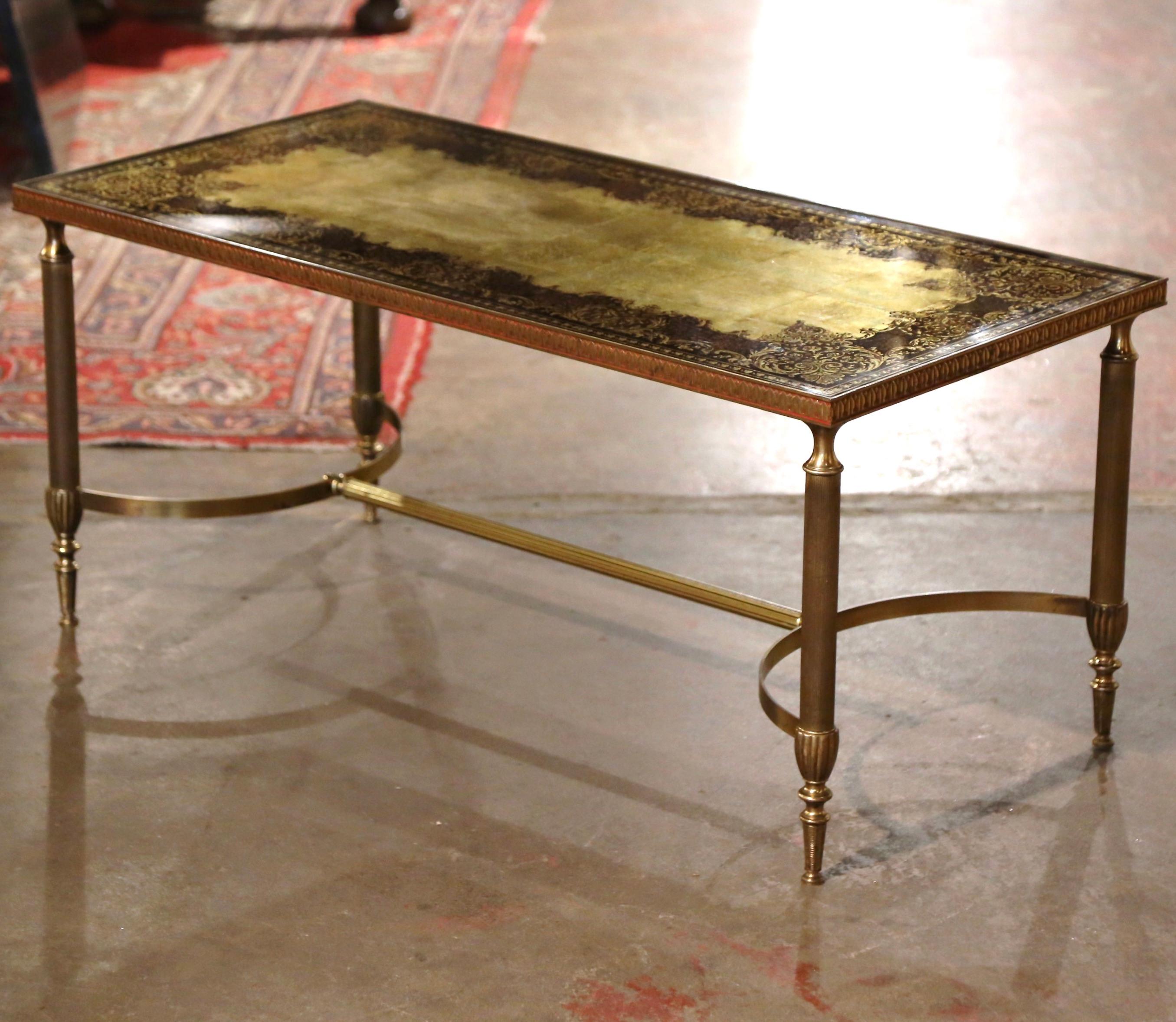 This elegant and slender cocktail table was crafted in France by Maison Baguès circa 1960; the rectangular table stands on four fluted brass legs embellished with ring decor, over an arched bottom stretcher dressed with end finials. The surface is