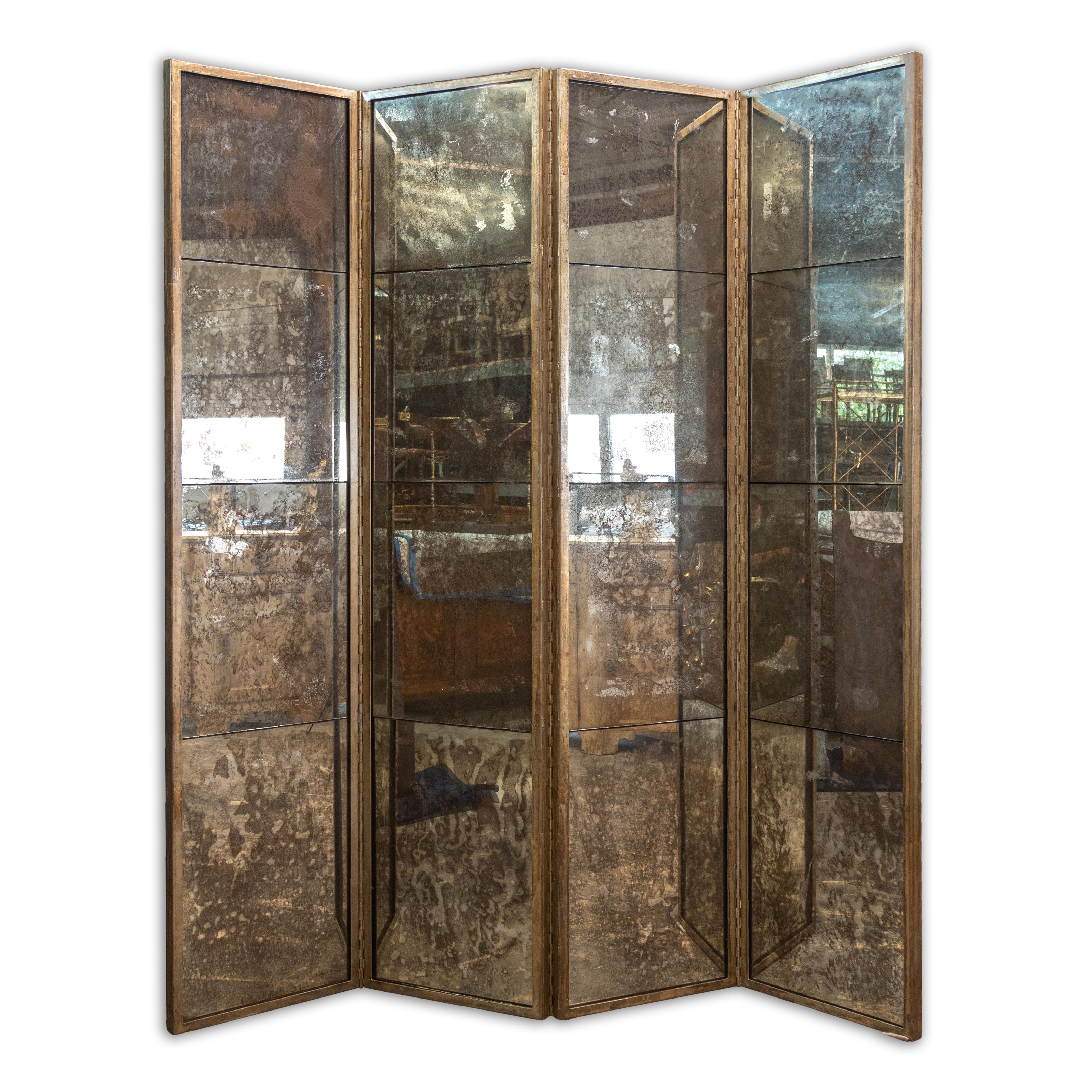 A French four-panel mirrored screen from the Midcentury period with heavy antiquing and metal frame. Imbue your living space with an air of vintage opulence with this French four-panel mirrored screen, a Midcentury piece that gracefully weaves