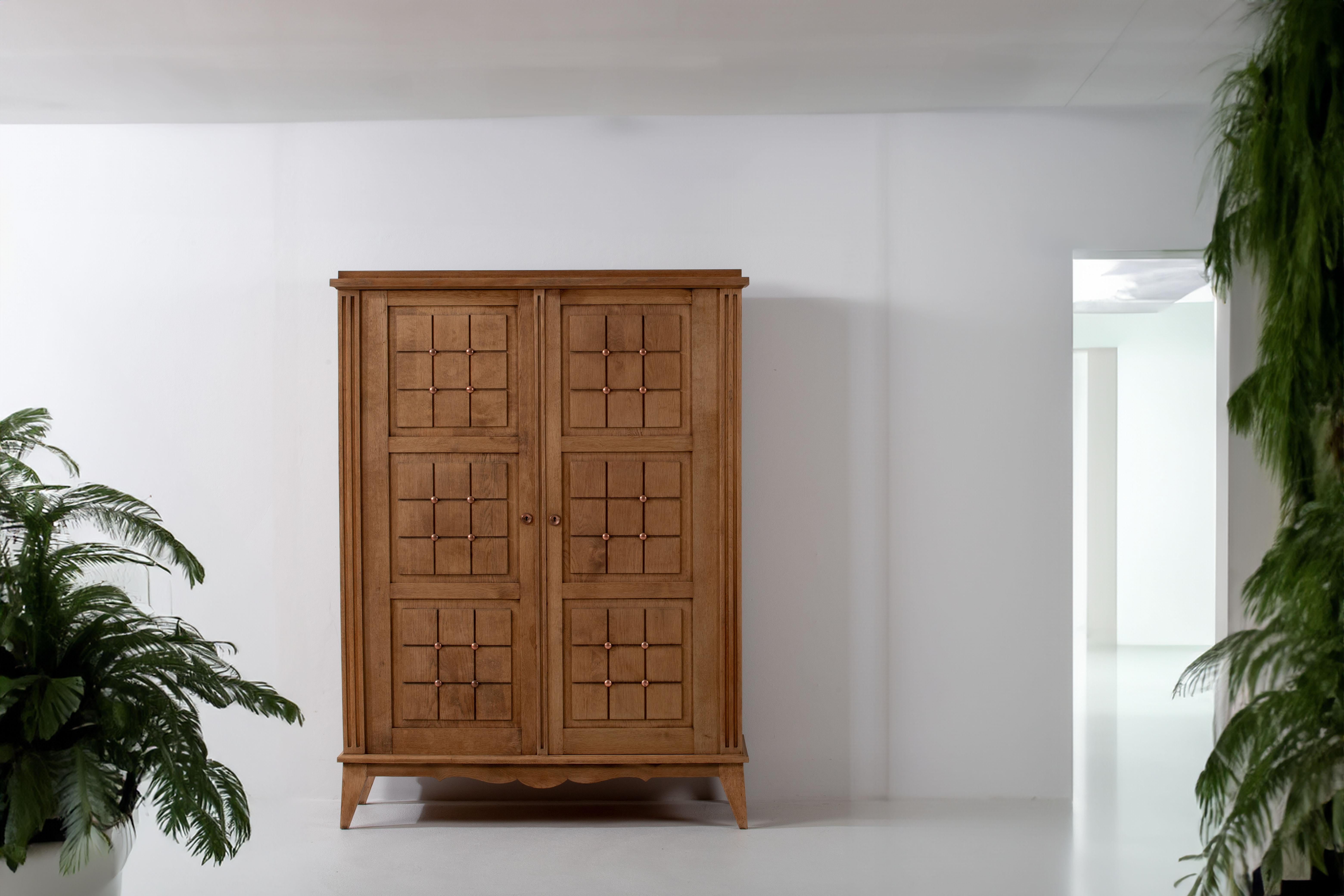 Der Schrank aus massiver Eiche aus den 1950er Jahren besticht durch sein ausgeprägtes quadratisches Muster auf den Türen, das von der kühnen Ästhetik des Brutalismus inspiriert ist. Die mit viel Liebe zum Detail gefertigte Garderobe versprüht einen