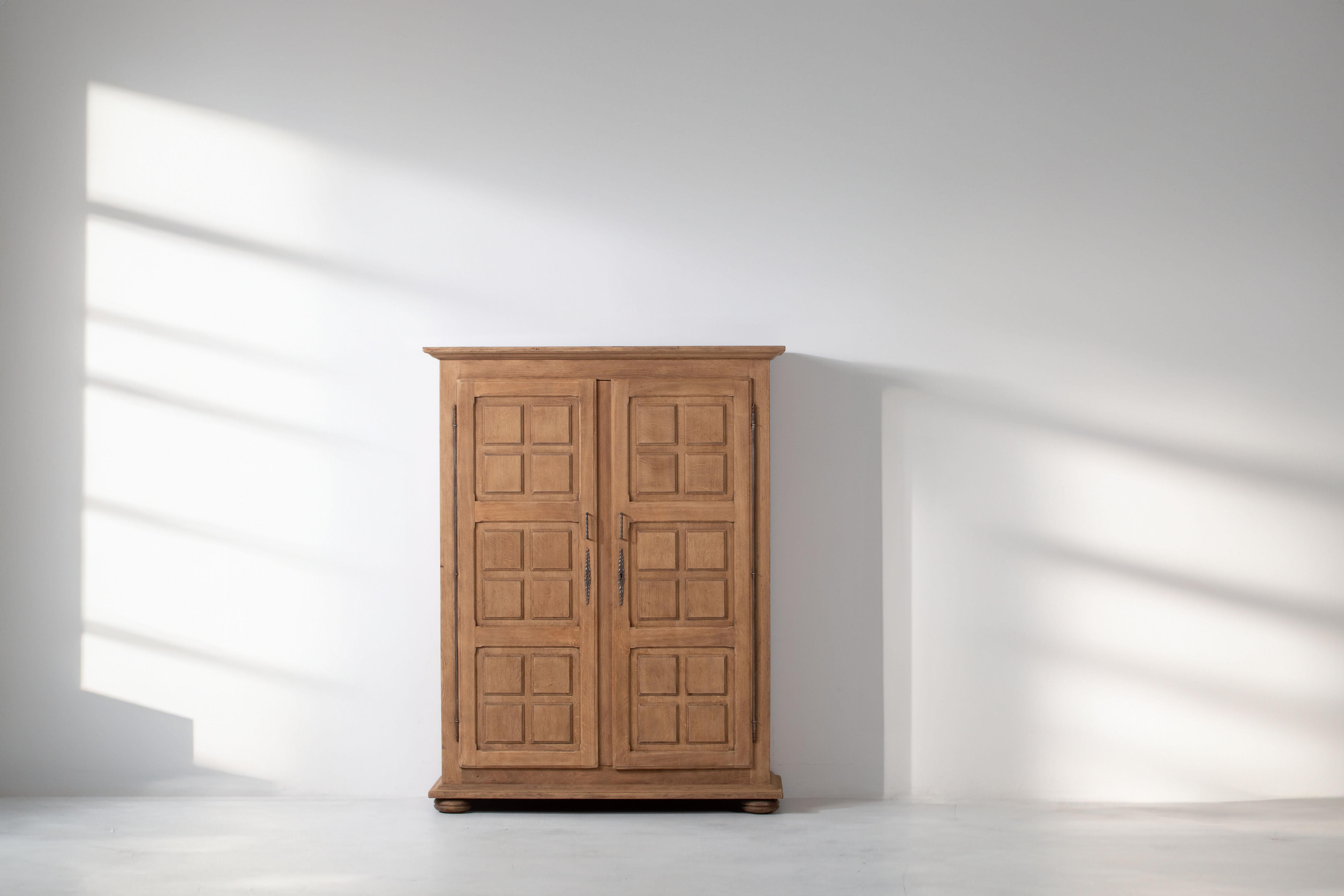 Der Schrank aus massiver Eiche aus den 1950er Jahren besticht durch sein ausgeprägtes quadratisches Muster auf den Türen, das von der kühnen Ästhetik des Brutalismus inspiriert ist. Die mit viel Liebe zum Detail gefertigte Garderobe versprüht einen
