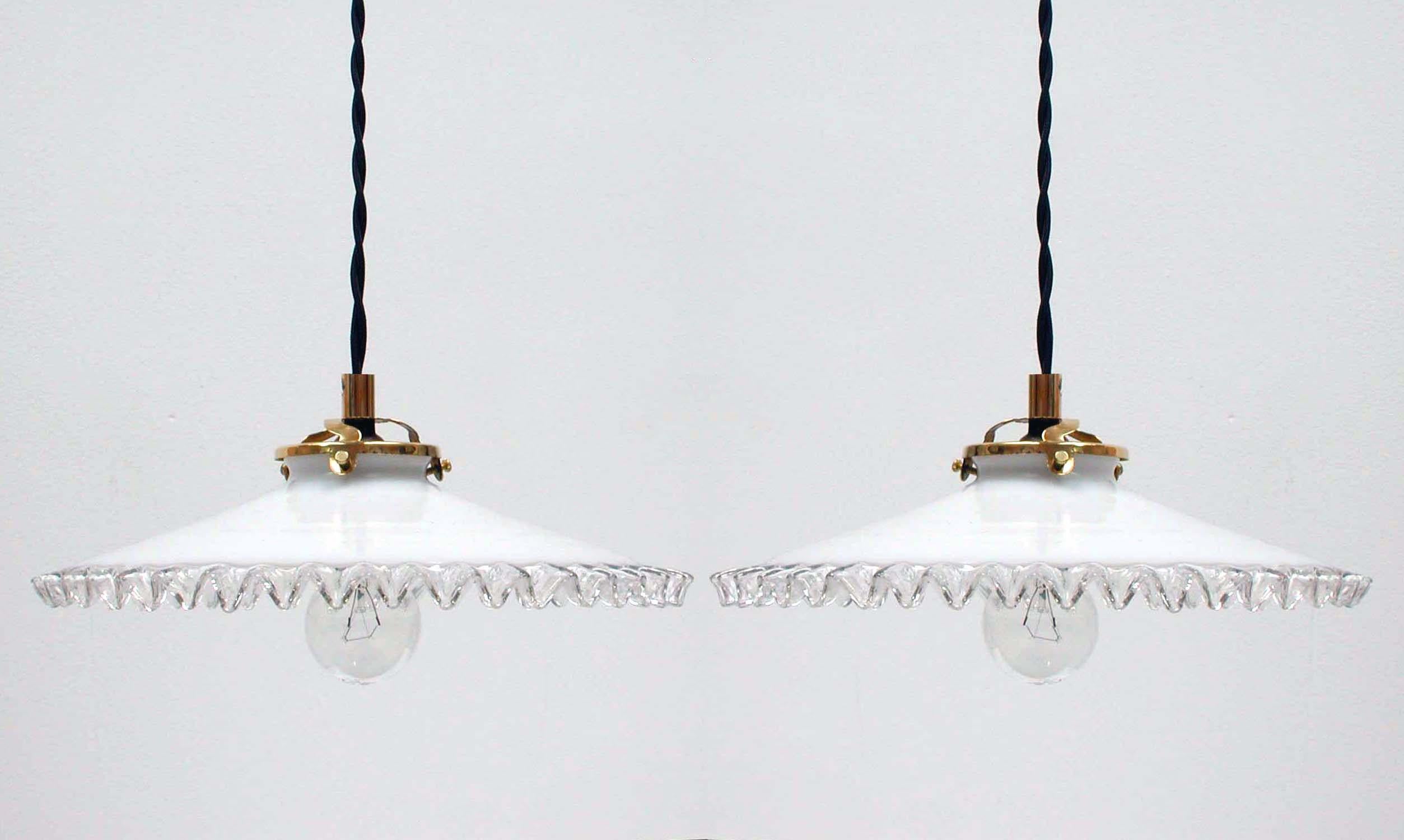Diese Pendelleuchten wurden in den 1950er Jahren in Frankreich hergestellt. Die Lampen haben Lampenschirme aus weißem Opalglas mit Falten und Fassungen aus Messing. Sie verfügen über französische B22-Steckdosen und wurden mit neuen Stoffkabeln neu