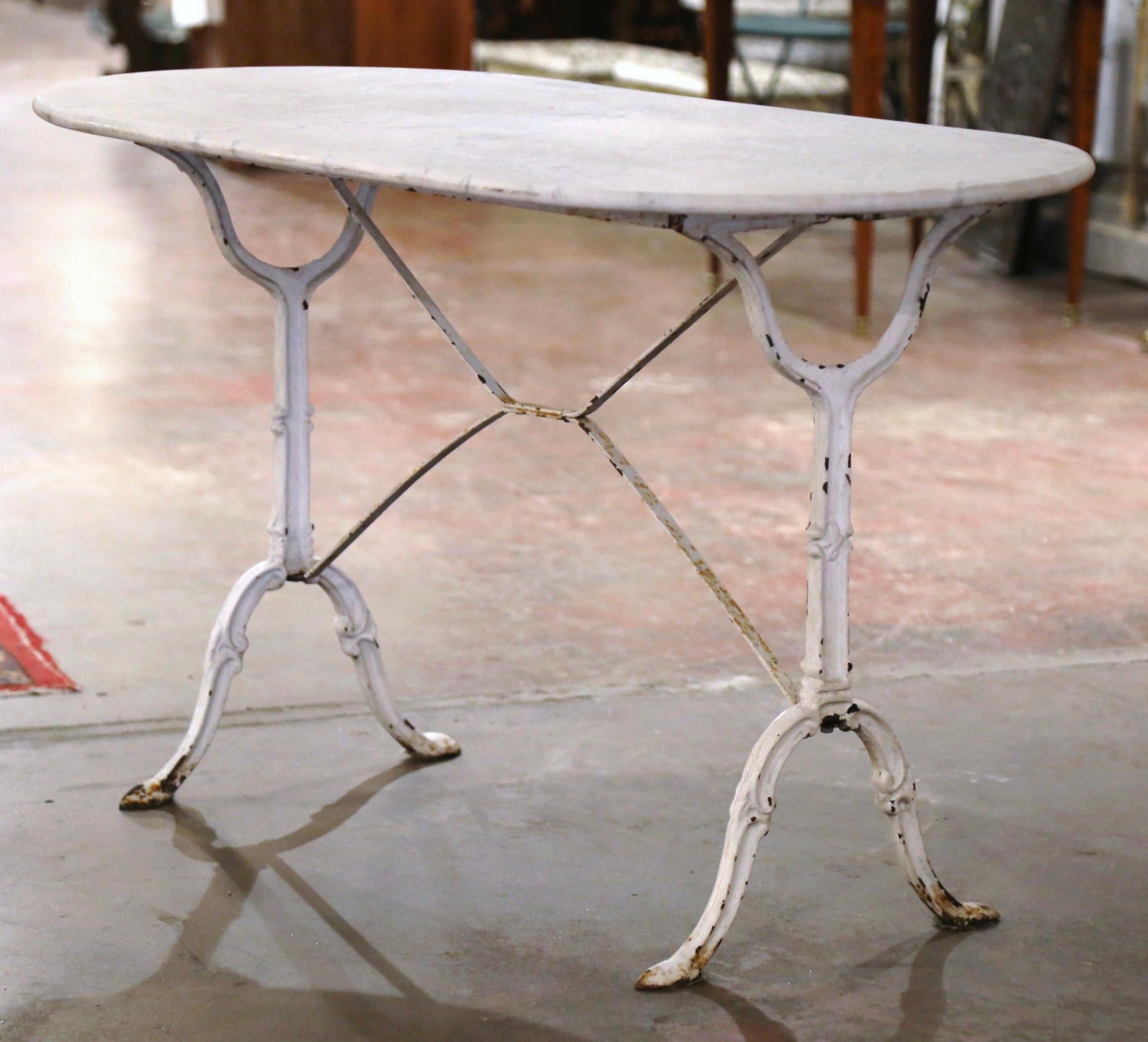Decorate a patio or covered porch with this elegant antique oval bistrot table. Crafted in France circa 1950, the cast iron table sits on a trestle base with elegant scroll legs ending with hoof feet, and joined together with a double decorative