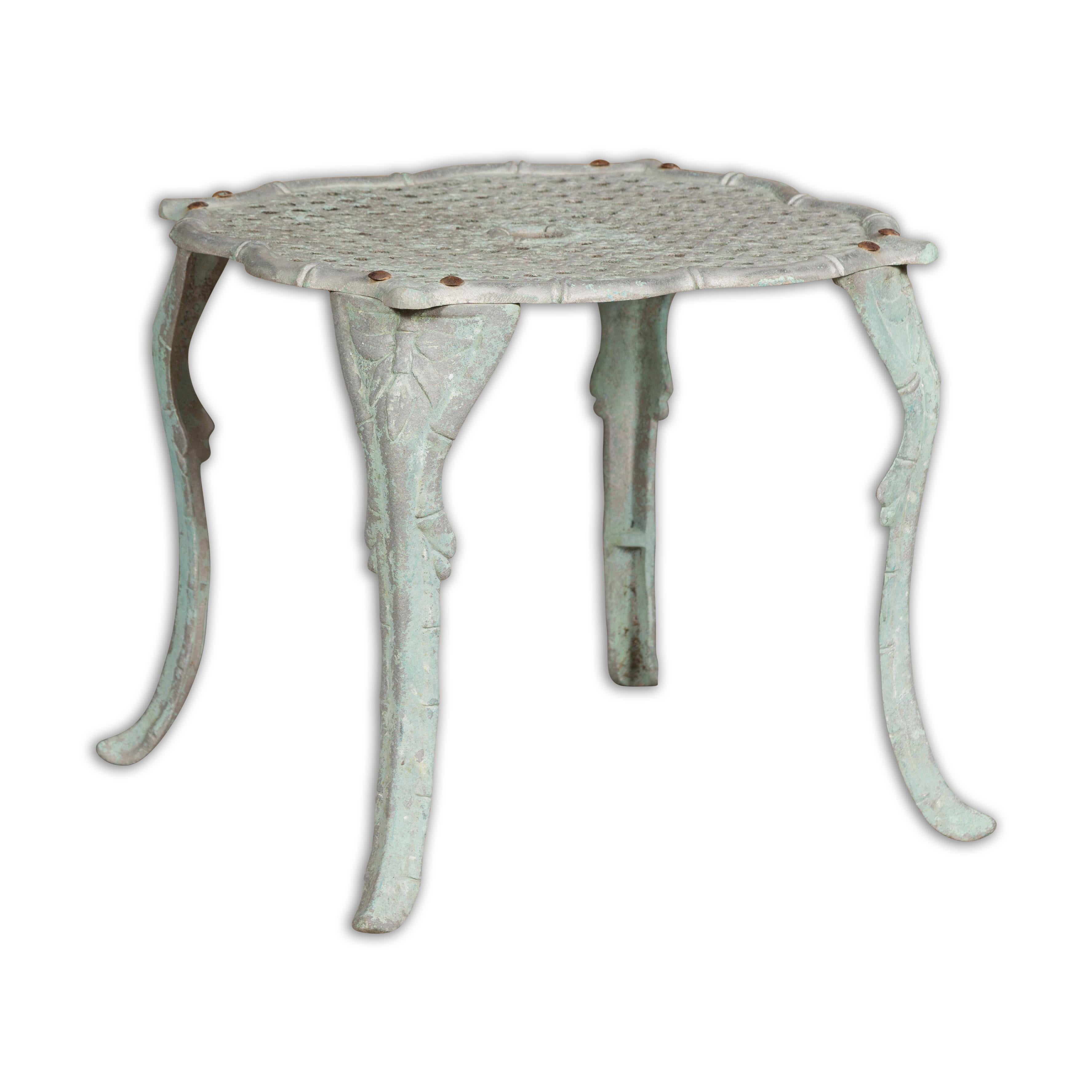 A French painted metal low side table from the Midcentury period, with blue green finish, wicker inspired top and cabriole legs. This French Midcentury side table is a delightful blend of whimsy and elegance. Crafted from painted metal, it exudes a