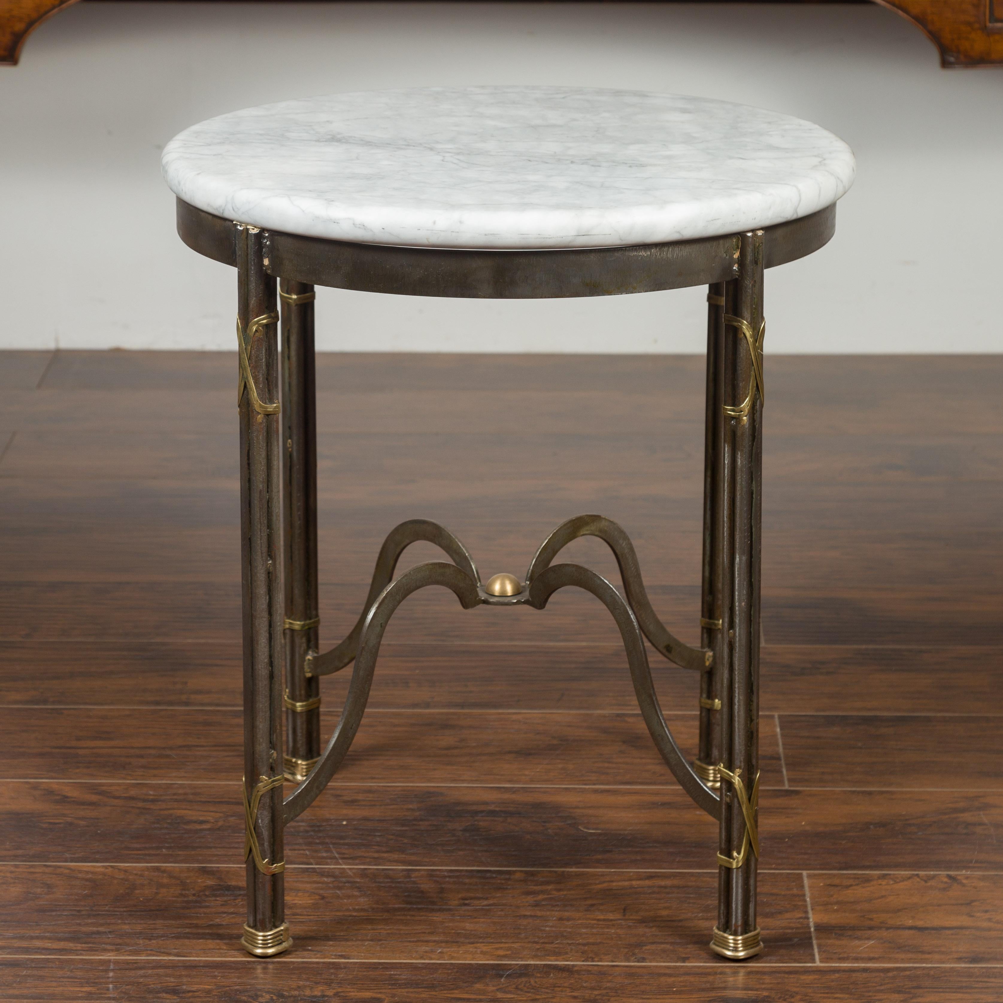 A vintage French polished steel side table from the mid-20th century, with circular white marble top and brass accents. Created in France during the midcentury period, this side table features a round white veined marble top, sitting above an