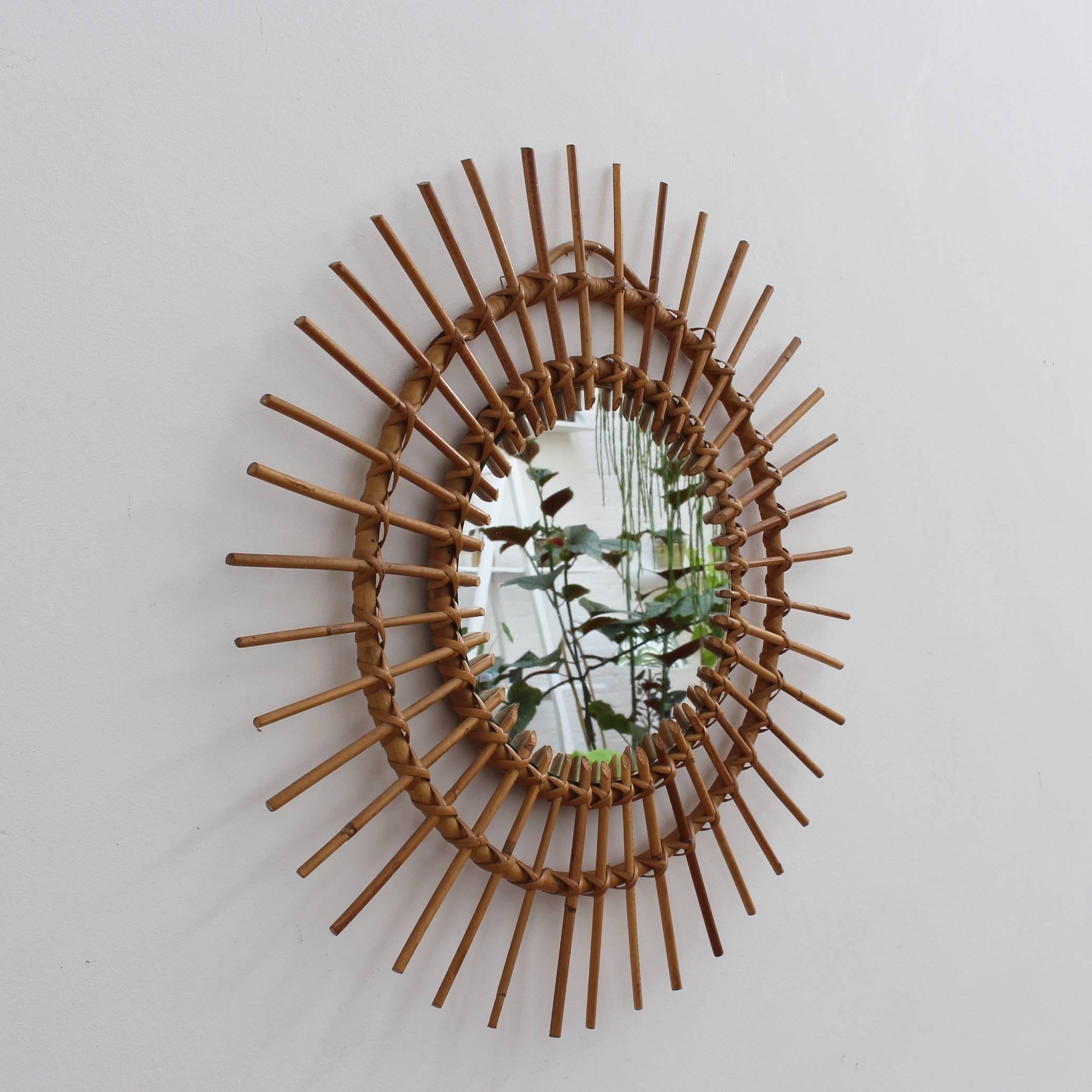 Midcentury French rattan sunburst mirror, circa 1960s. A vintage collectible classic. The mirror is in good condition consistent with its age and use showing characterful blemishes and light wear on its spokes and frame. The glass is still youthful