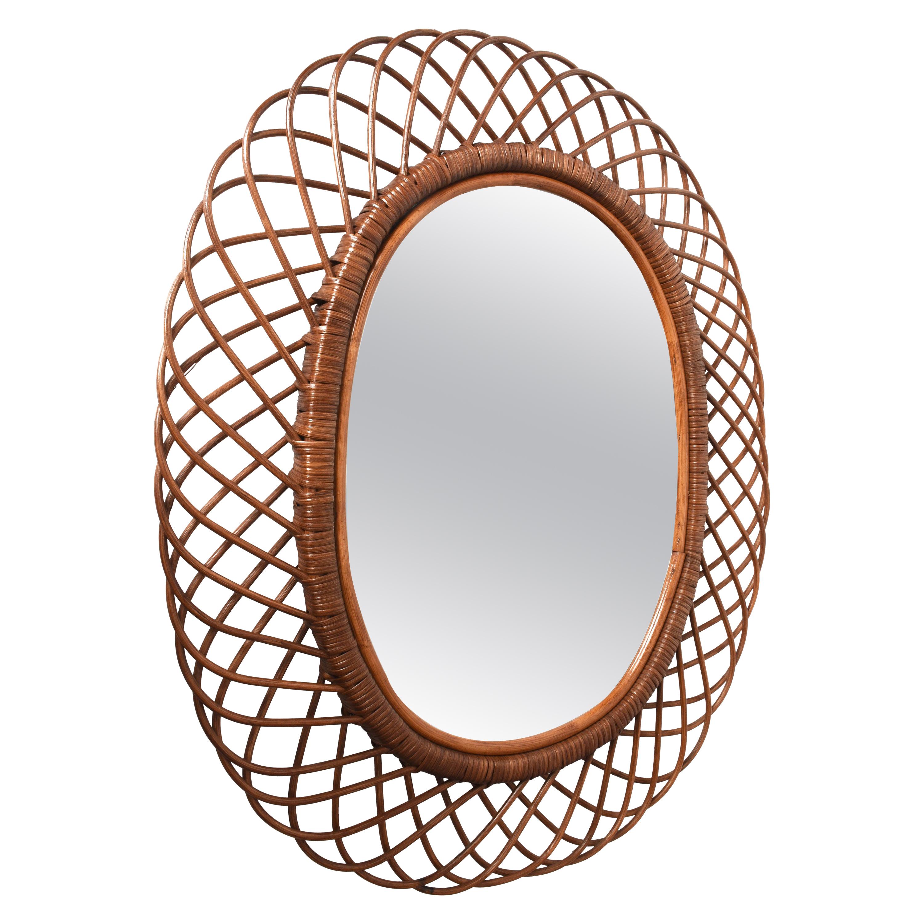 Amazing midcentury French Riviera rattan and bamboo oval mirror. This marvellous item was produced in Italy during 1960s.

This decorative oval mirror is unique as it has a curved rattan beam and bamboo double frame, a solid internal one and an