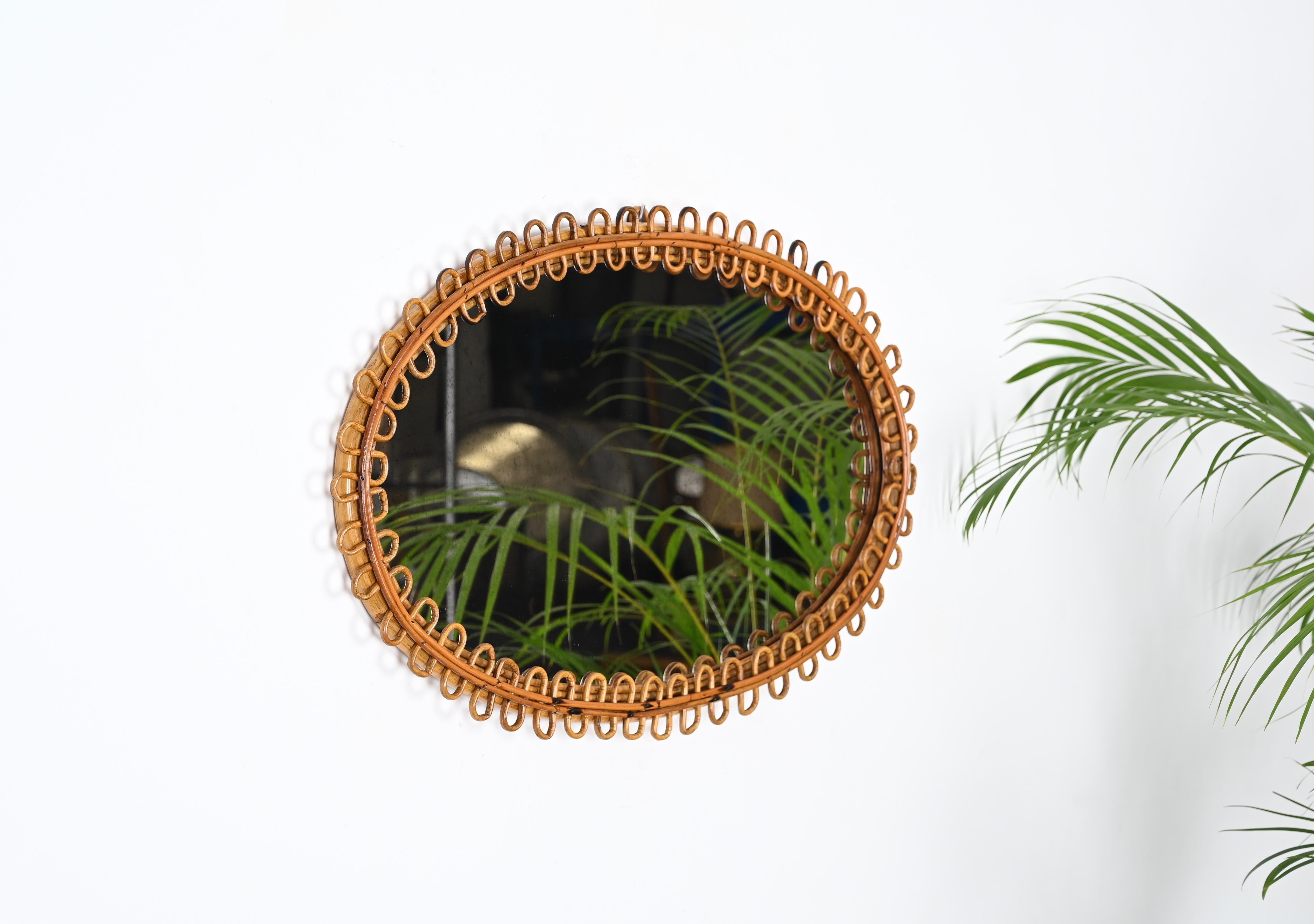 Fantastic large oval mirror with curved rattan beams and bamboo frame. This beautiful French Riviera style mirror was produced in Italy in the 1960s.

The mirror features a gorgeous oval double frame in curved bamboo enriched all around by curved