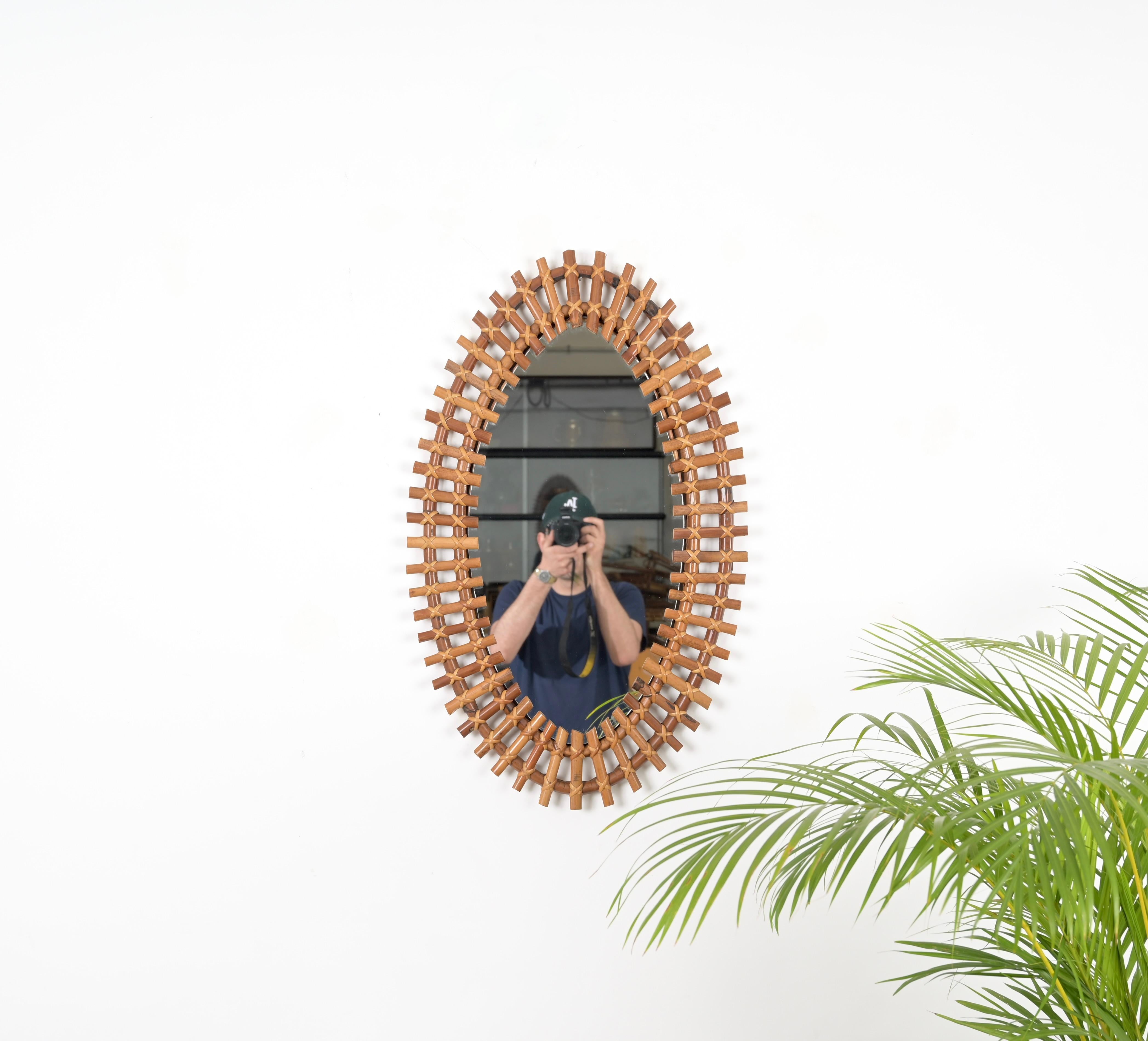 Dieser wunderschöne große ovale Wandspiegel aus Bambus, Rattan und Weide wurde in den 1960er Jahren in Italien hergestellt. 

Dieser reizende Spiegel hat ein atemberaubendes  Doppeltes Gestell aus gebogenem Rattan, durchzogen von kleinen