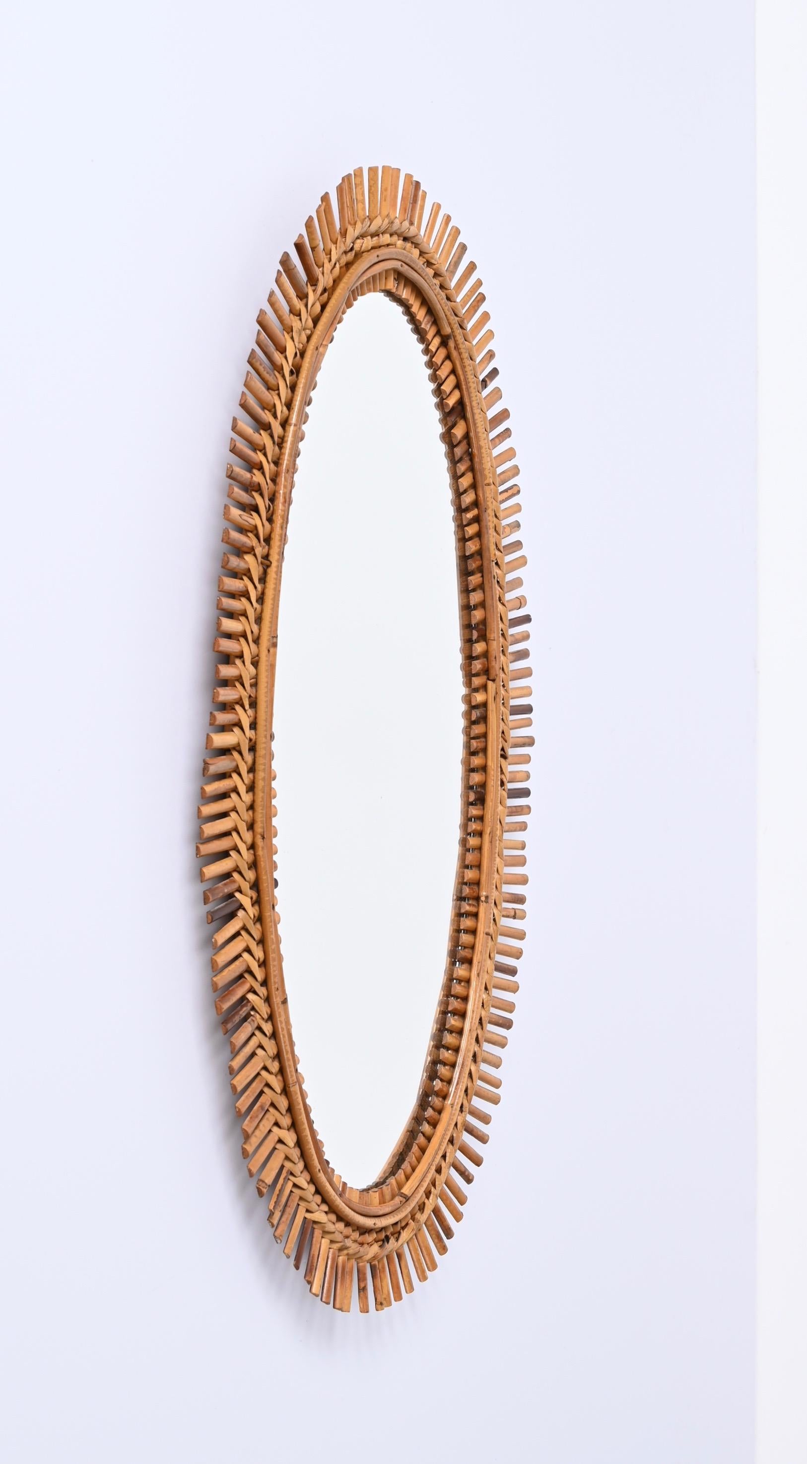 Cote d'Azur oval wall mirror in bamboo, rattan and wicker, made in France in the 1960s. It is attributed to the mastery of Franco Albini.

This fantastic mirror features a double frame in rattan crossed by small bamboo inserts, the whole is kept