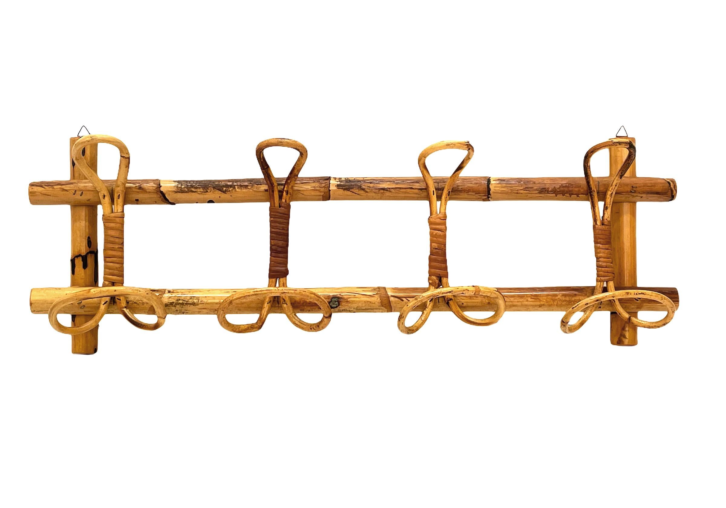 Amazing French Riviera midcentury rattan and bamboo coat hanger. This wonderful piece was made in Italy during the 1960s.

This unique item features a structure in bamboo canes and four rattan upper hooks and lower hooks for hanging coats.

The