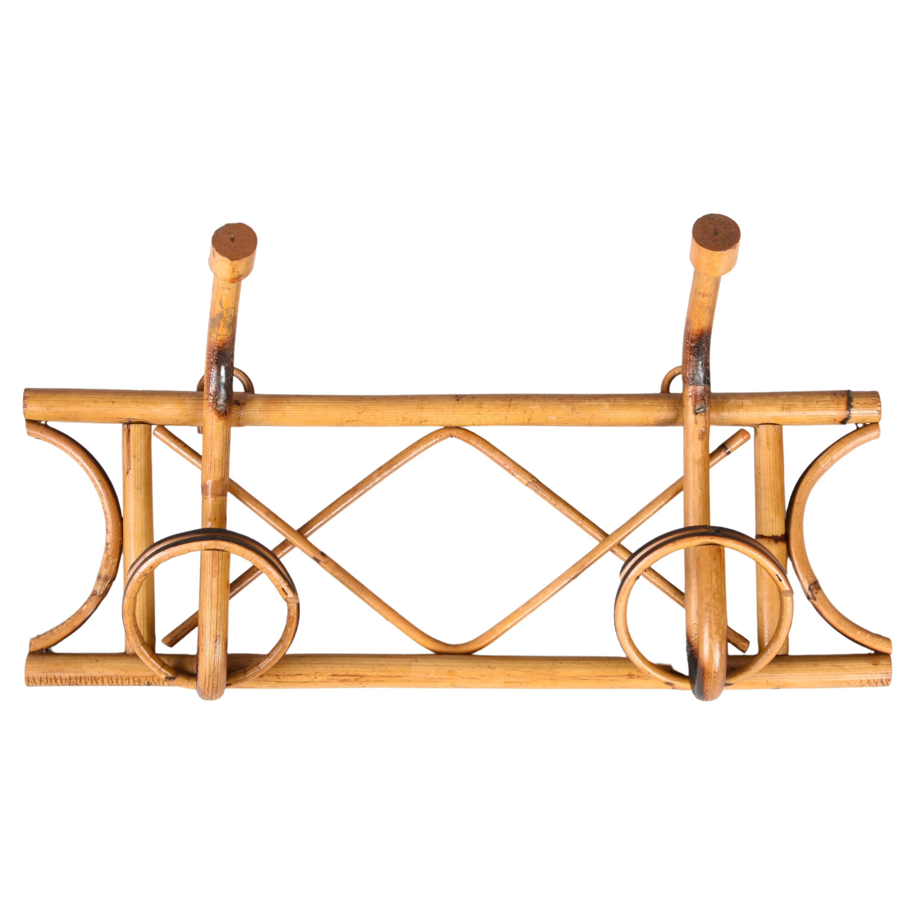 Amazing French Riviera midcentury rattan and bamboo coat hanger. This wonderful piece was made in Italy during the 1960s.

This unique item features a structure in bamboo canes and two brown rattan upper hooks and lower hooks for hanging coats.