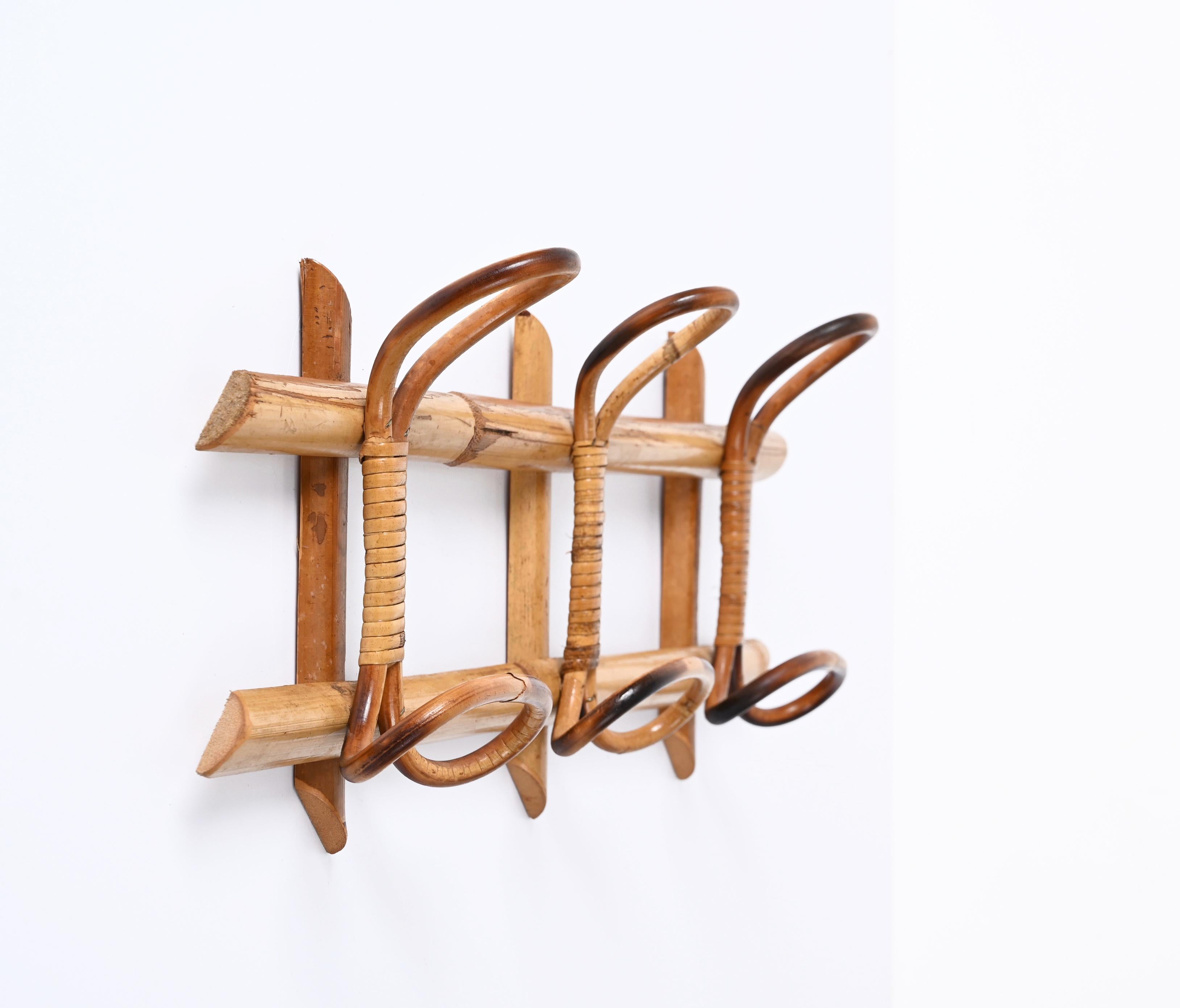 Amazing French Riviera midcentury rattan and bamboo coat hanger. This wonderful piece was made in Italy during the 1960s.

This unique item features a structure in bamboo canes and four brown rattan upper hooks and lower hooks for hanging coats. The