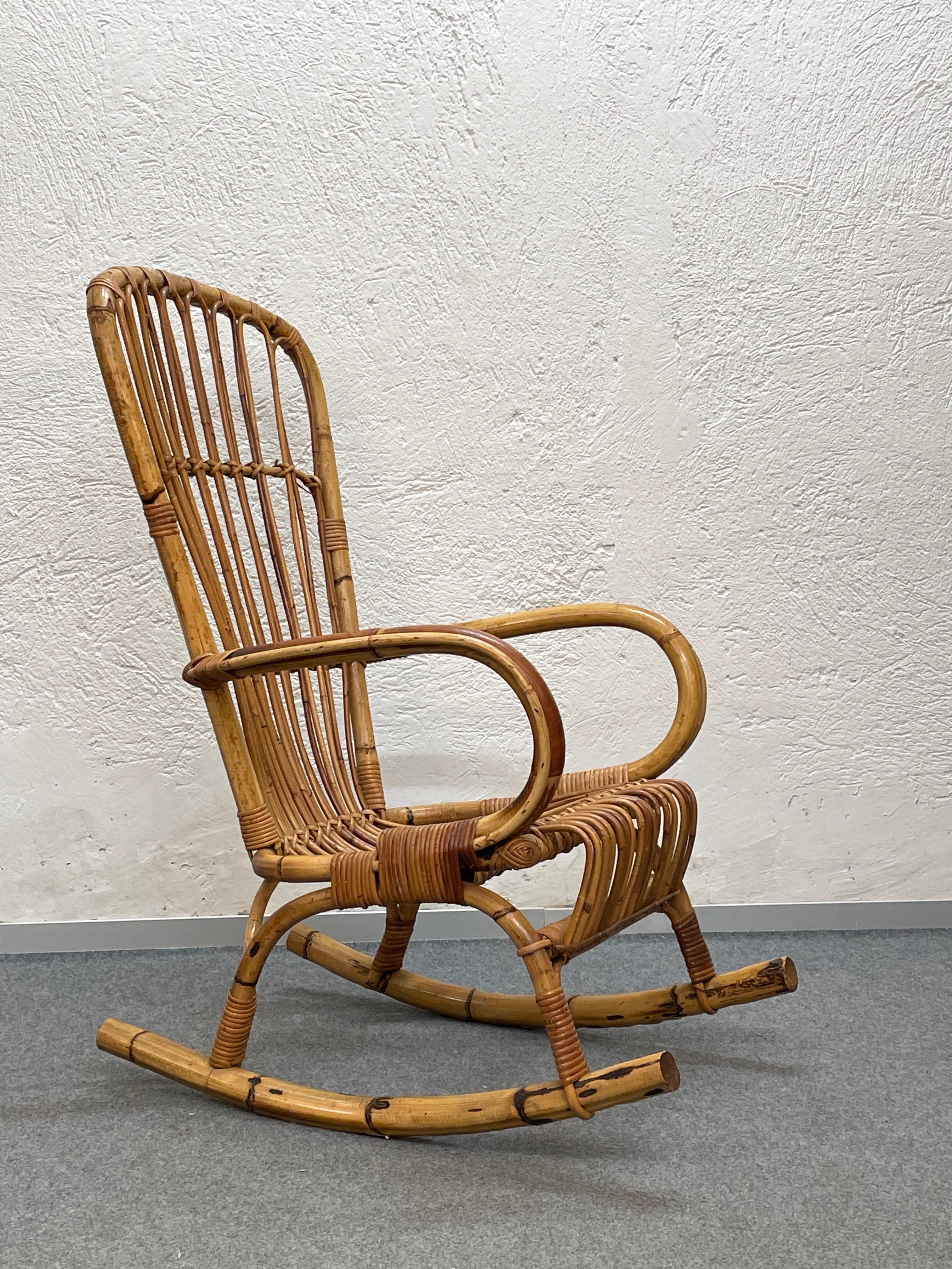 Elegant midcentury French Riviera rattan, bamboo and hand-woven wicker rocking chair. This fantastic piece was designed and manufactured in Italy during the 1960s.

This armchair has a beautiful structure in curved bamboo, enriched with beautiful