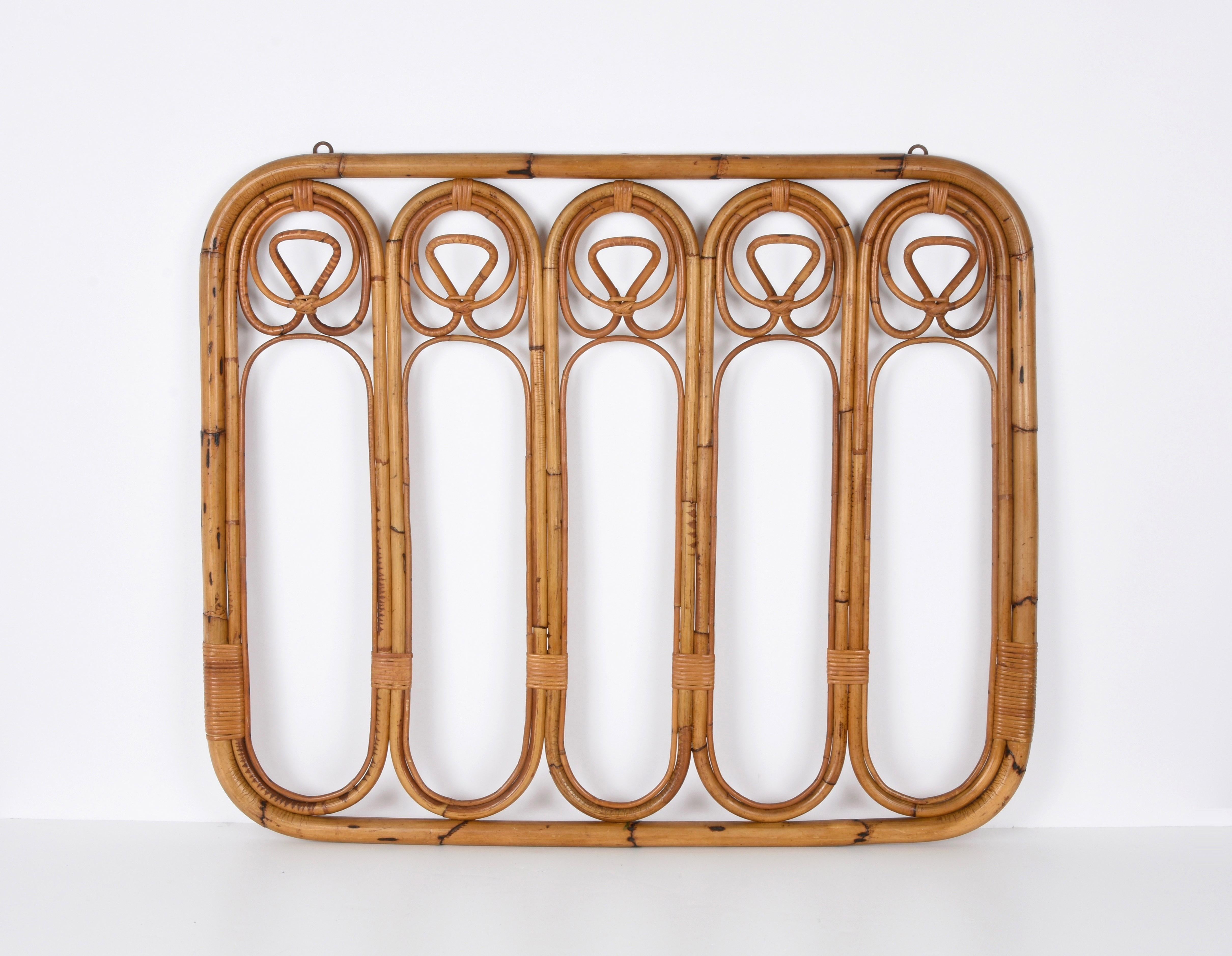 Incredible French Riviera midcentury rattan and bamboo coat hanger. This wonderful piece was made in Italy during the 1960s.

This unique item features a structure in bamboo canes with five rattan upper hooks and lower hooks for hanging