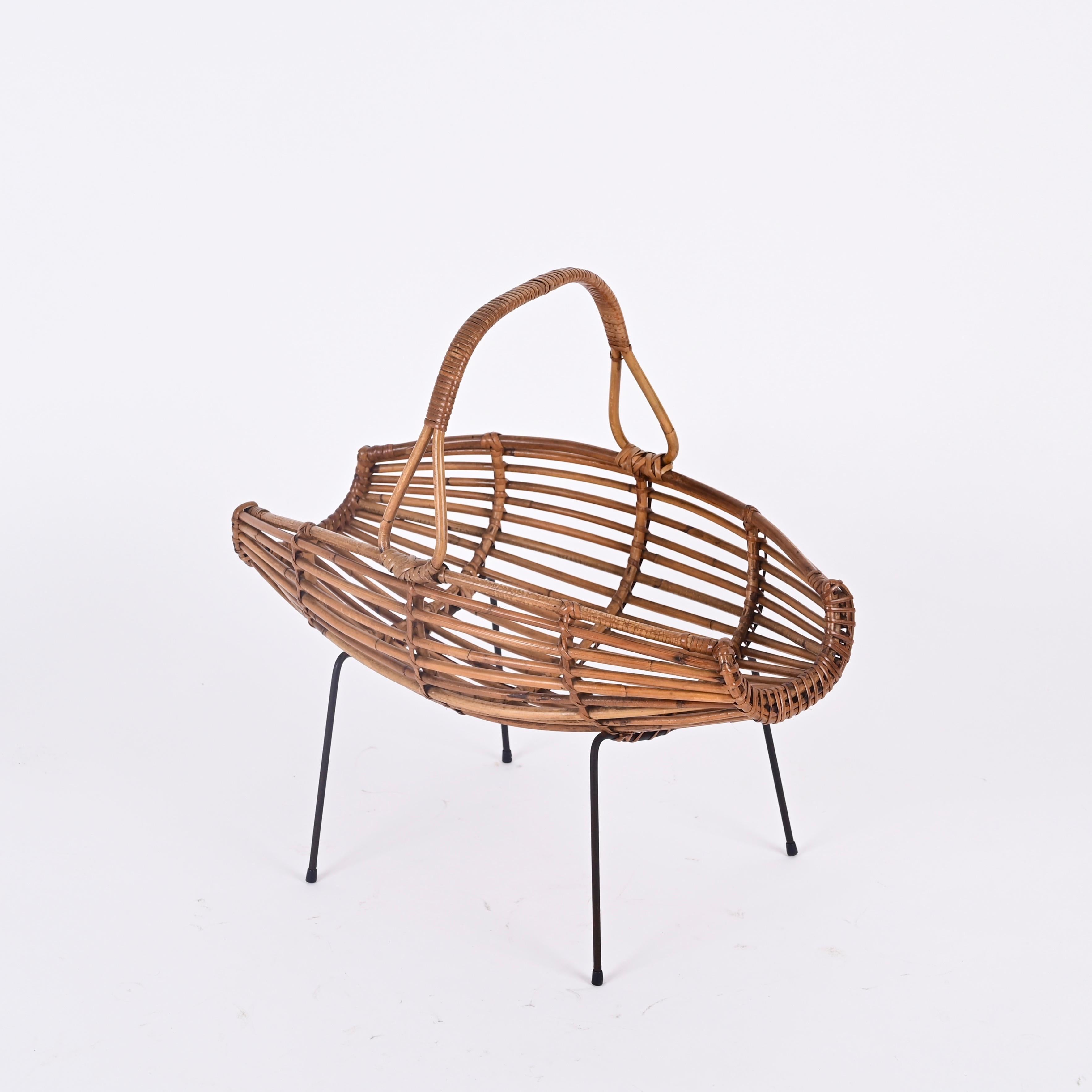 Stunning Midcentury French Riviera magazine rack made in a beautiful combination of curved rattan, woven wicker and enameled black iron. This charming object was made in Italy during the 1950s.

This delightful magazine rack feature a black enameled
