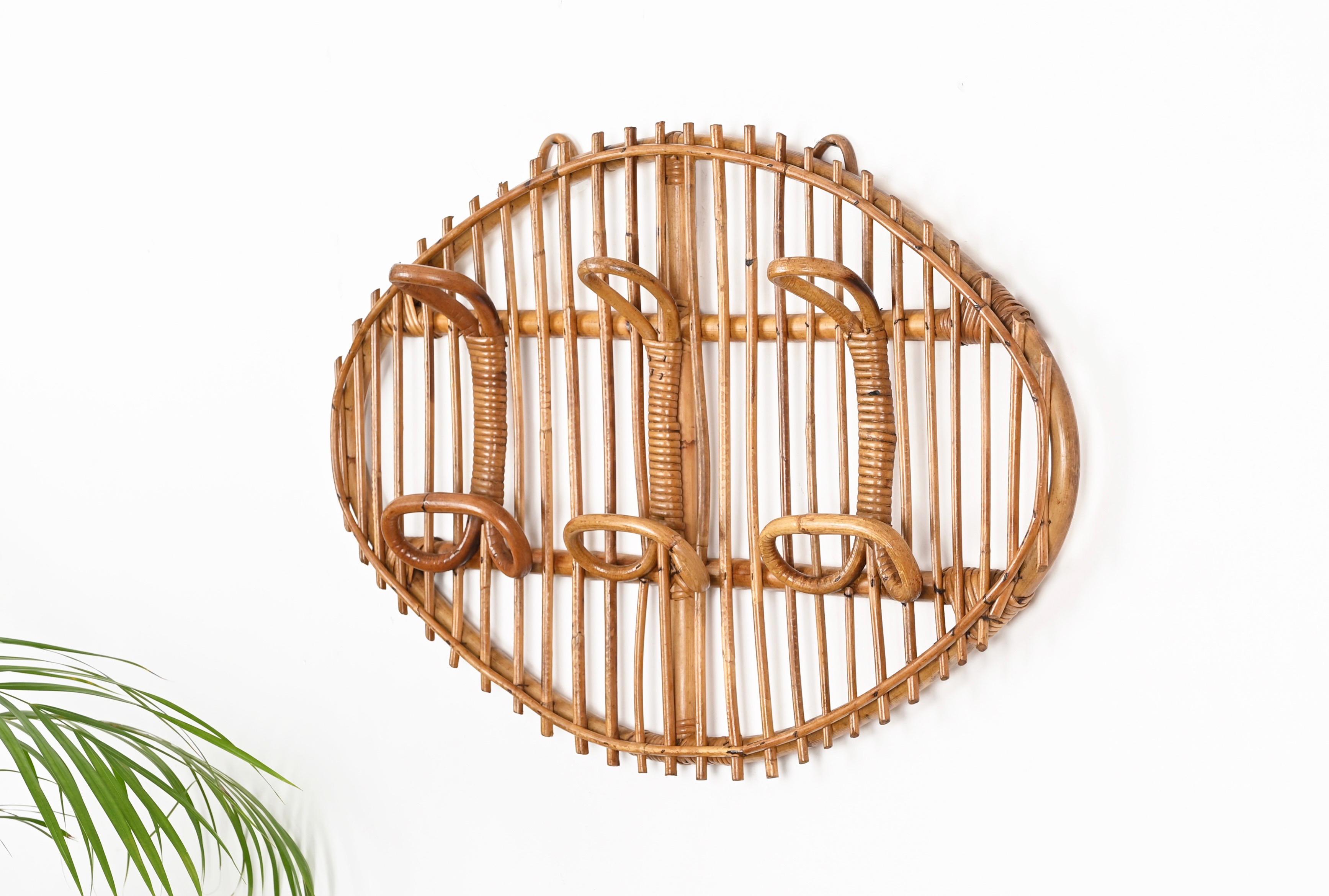 Gorgeous Mid-Century French Riviera style coat rack in curved rattan, bamboo and woven wicker. This delightful piece was designed in Italy during the 1960s.

This unique item features an oval frame in curved bamboo with three perfect hooks made in